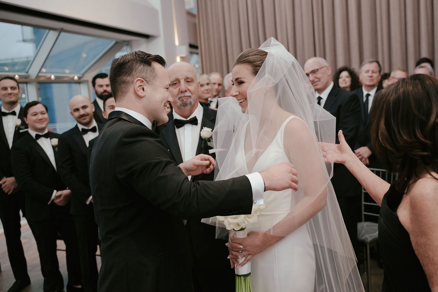 A wedding ceremony taking place in an elegant venue with guests watching as couple exchanges vows.