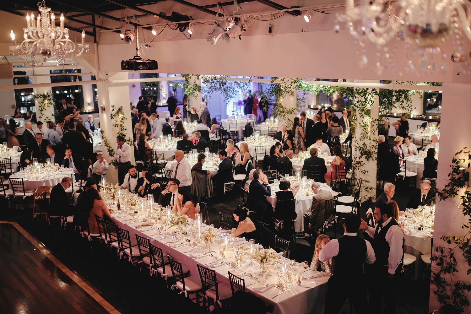 Elegant wedding reception venue with crystal chandeliers, long tables, and floral decorations.