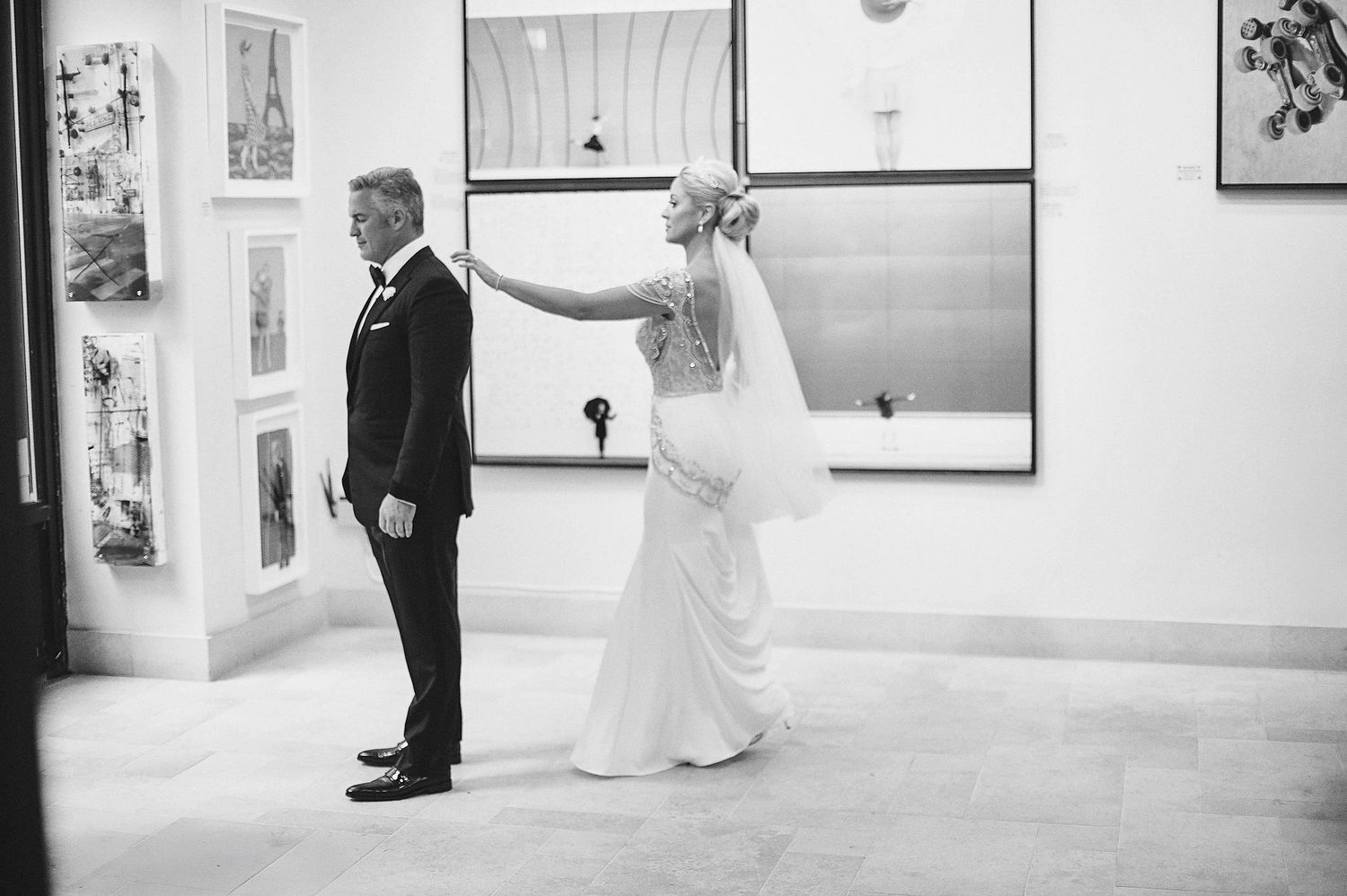 Black and white photo of a couple doing their first look moment before their wedding ceremony in an art gallery.