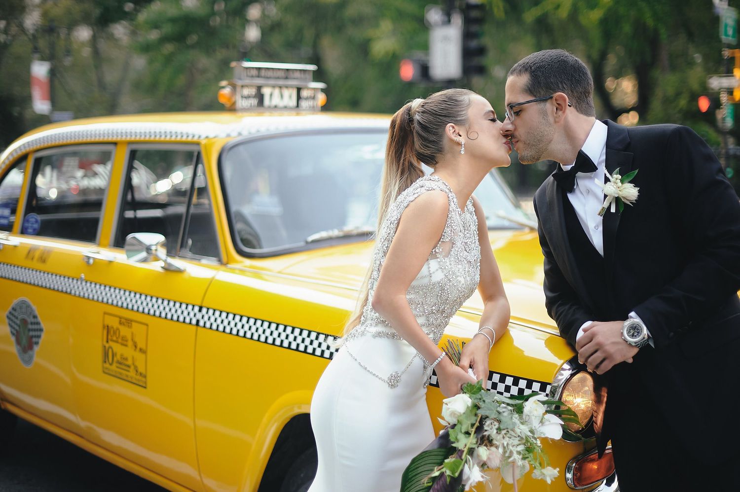 A couple shares a moment next to a classic yellow NYC taxi cab during their wedding photo session.