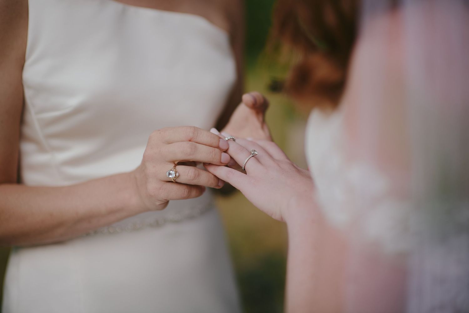 A close-up shot captures hands exchanging wedding rings during an intimate ceremony moment.