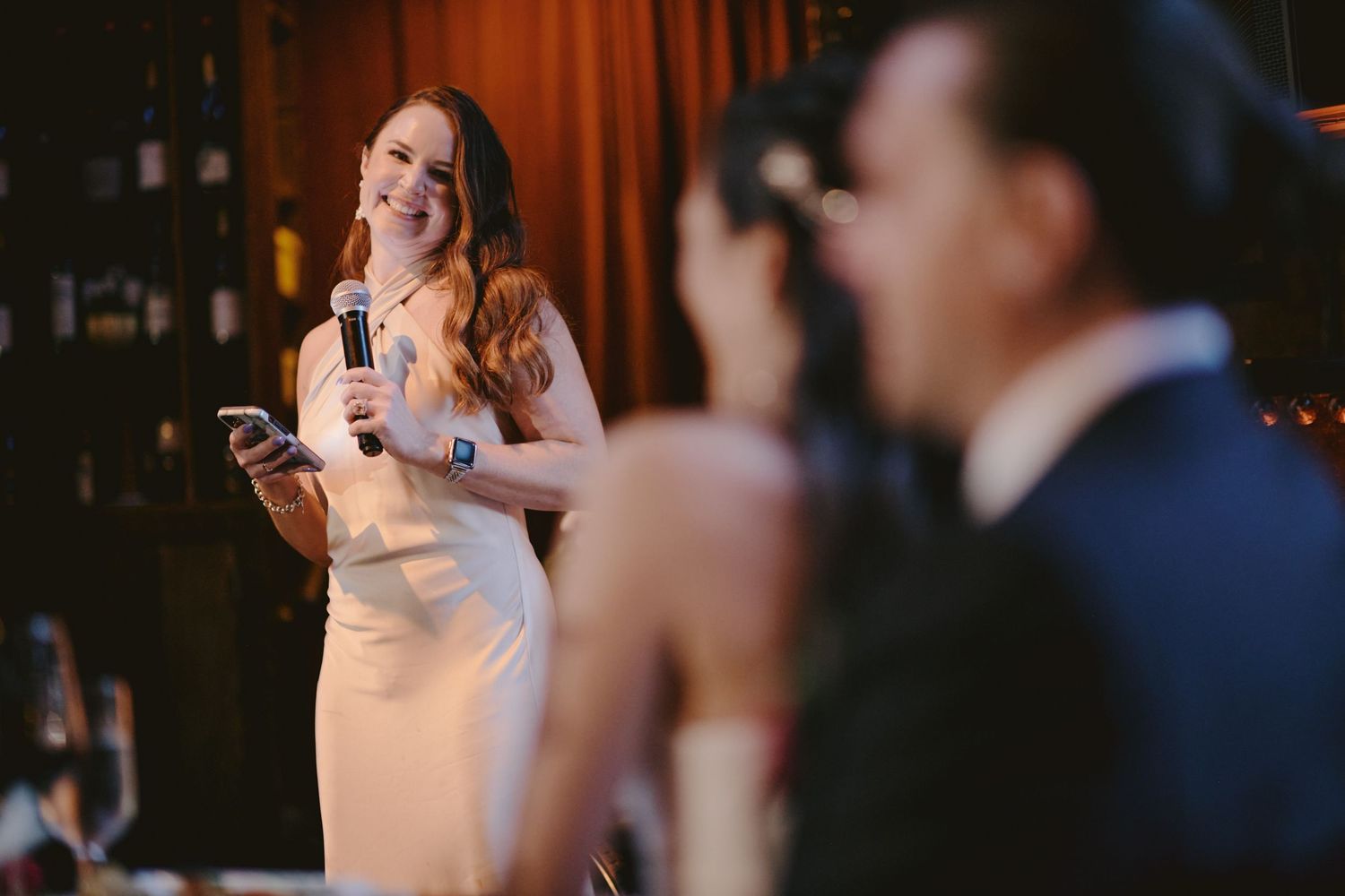 A speaker delivers an emotional speech at an evening reception while holding a microphone in an elegant venue.