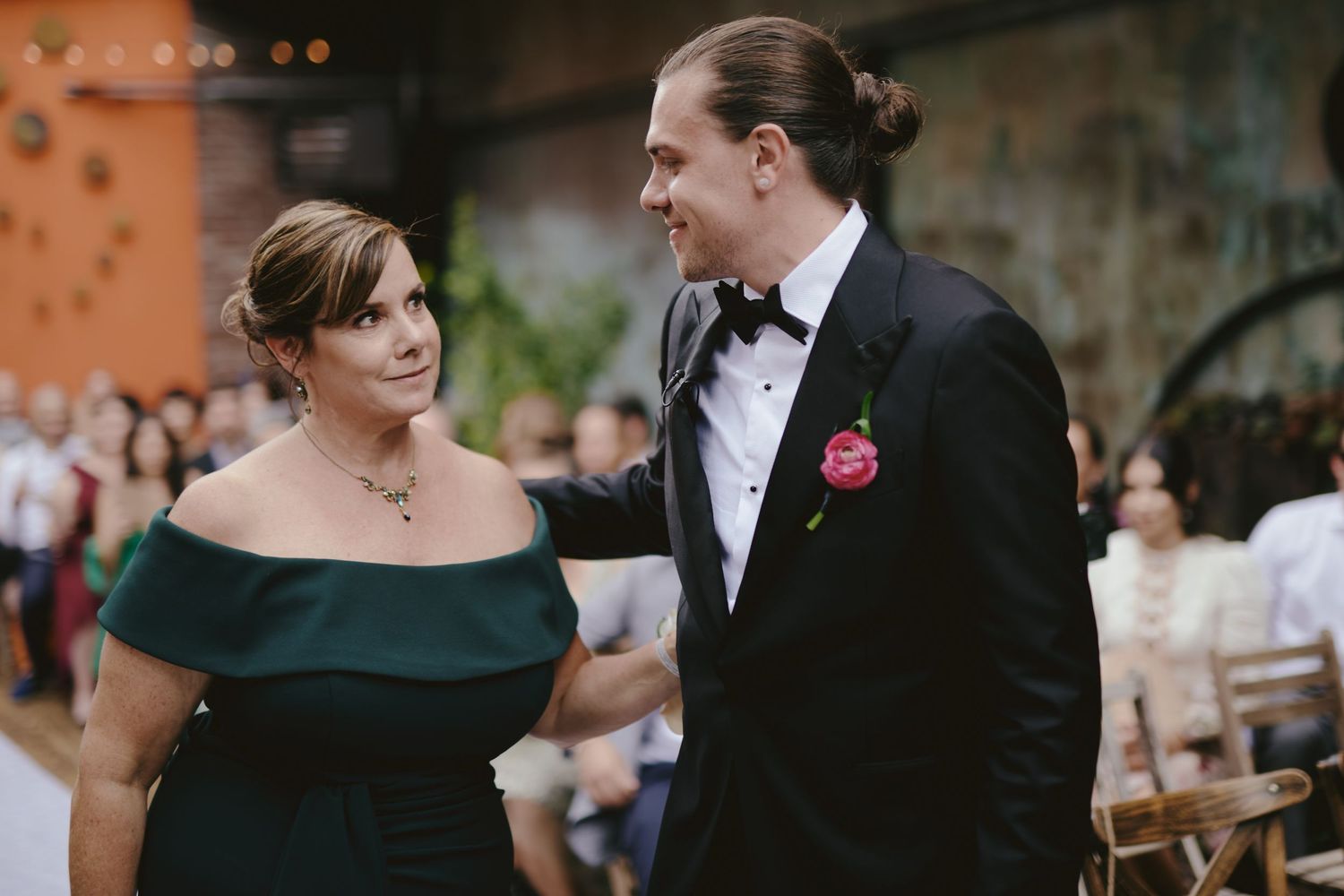 A couple in formal attire sharing a special moment at a wedding, with the woman in dark green and man in a tuxedo.