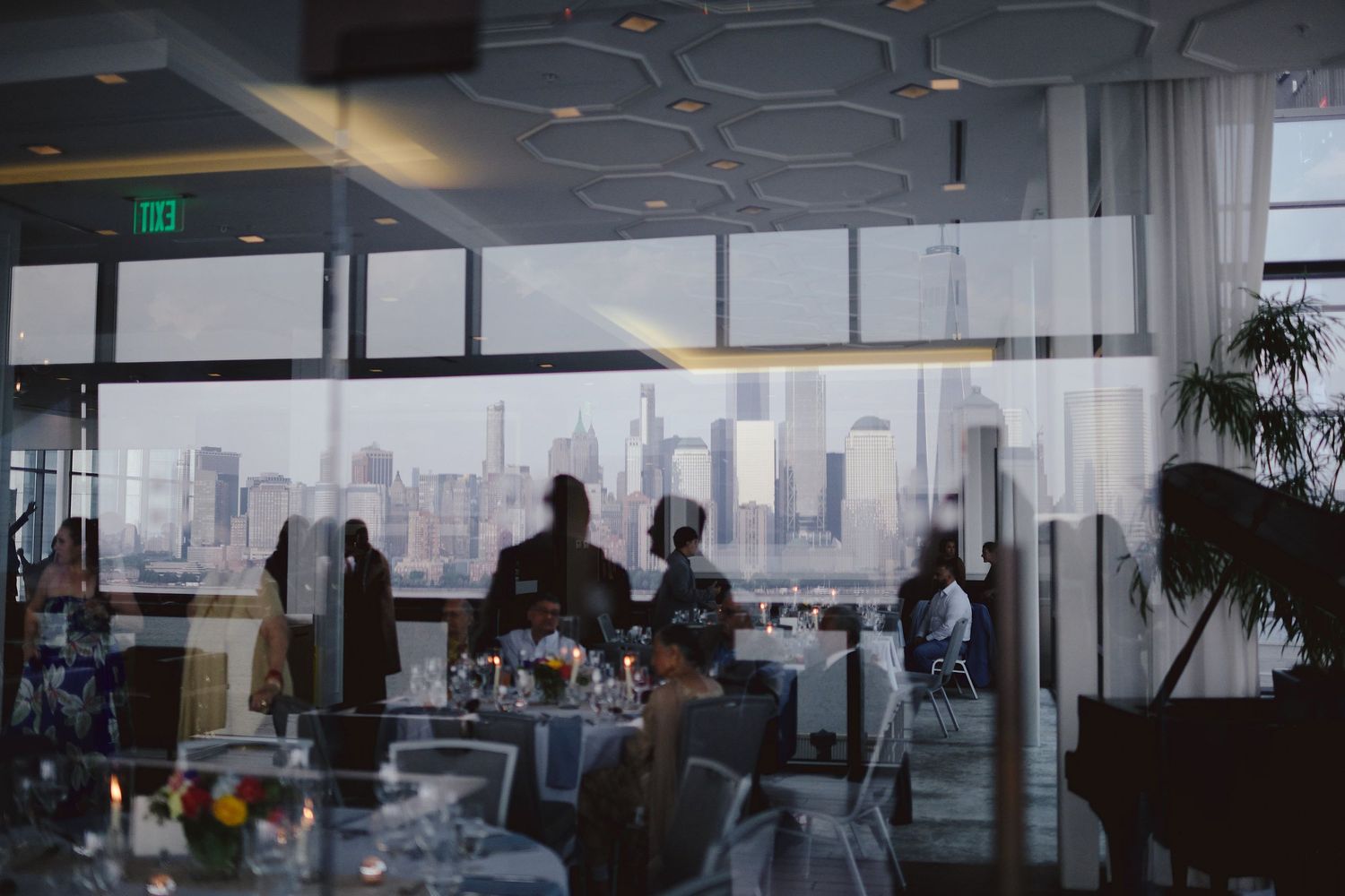 Business professionals gather in a modern office space with floor-to-ceiling windows overlooking a city skyline.