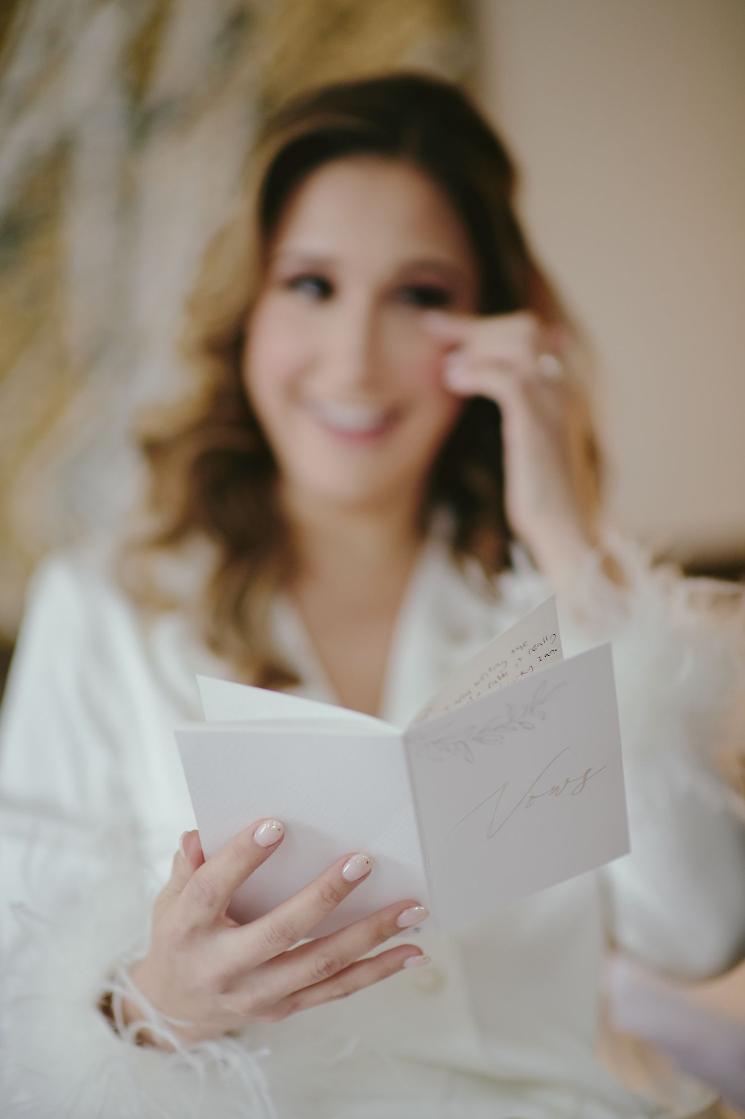 A person in white reads a note or card while seated during wedding preparations.