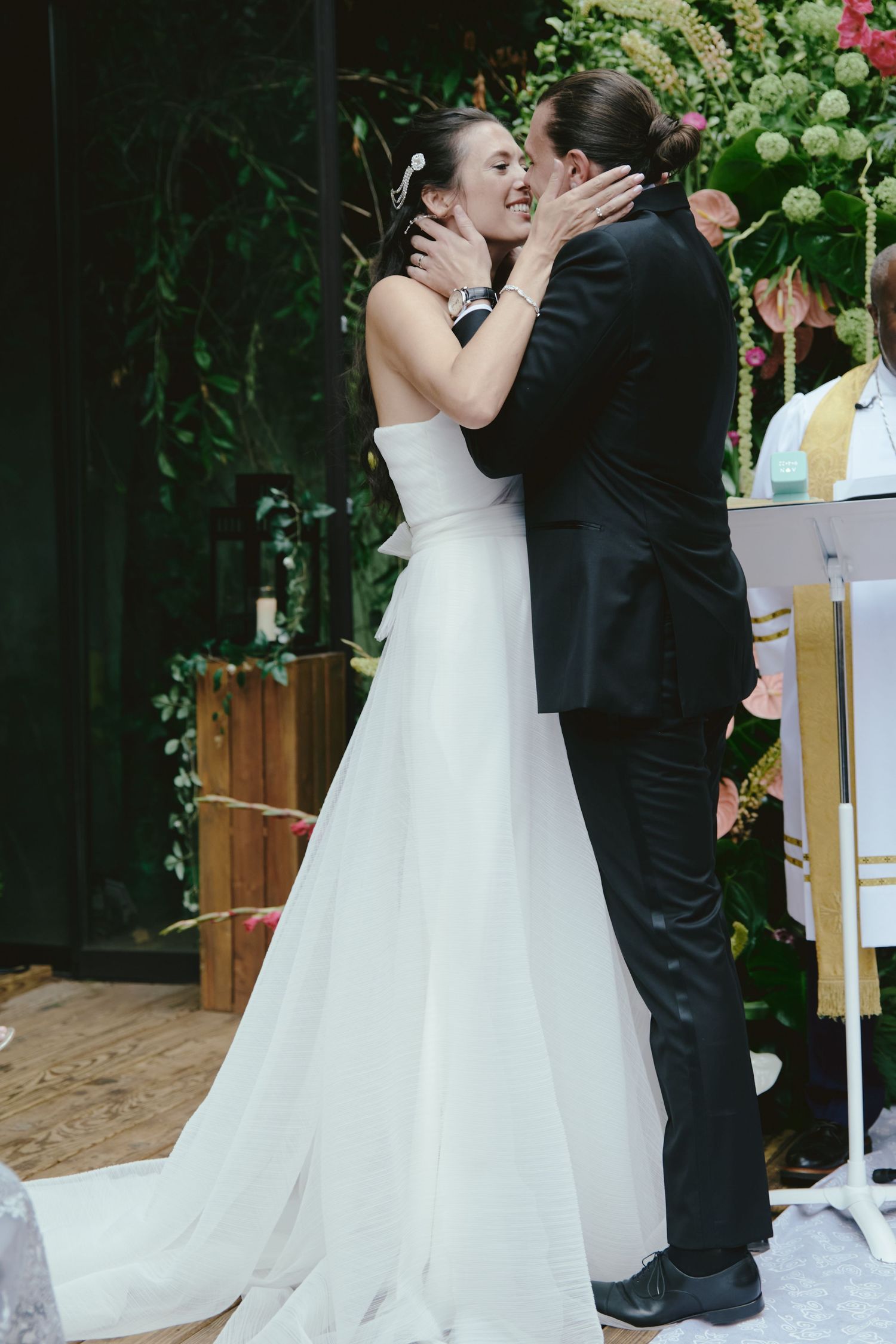 A bride and groom share an intimate embrace during their outdoor garden wedding ceremony.