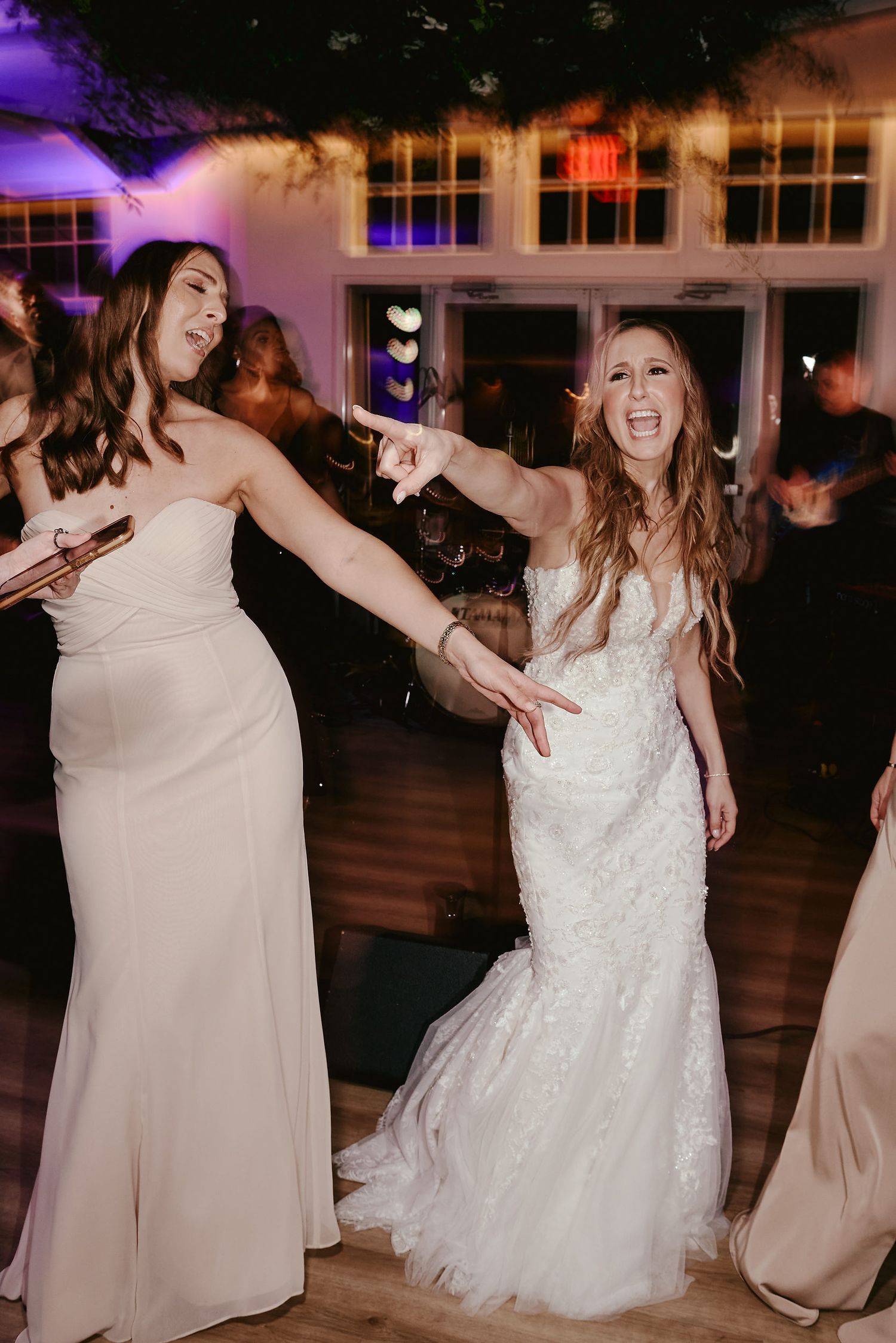 Wedding guests in evening gowns dancing and celebrating together on the dance floor during a reception party.