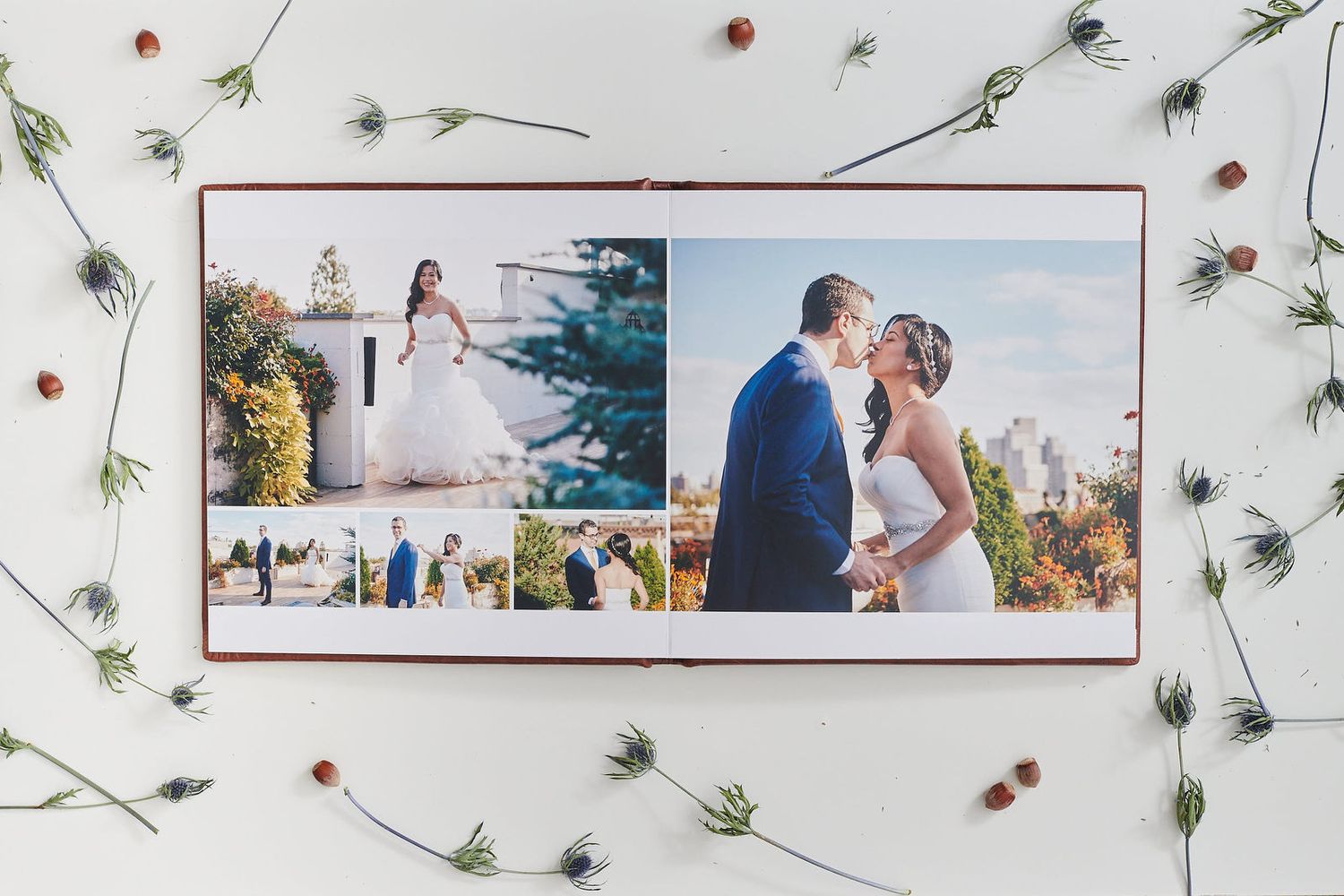 Wedding album photo book lying on white surface with delicate floral and botanical decorations scattered around.