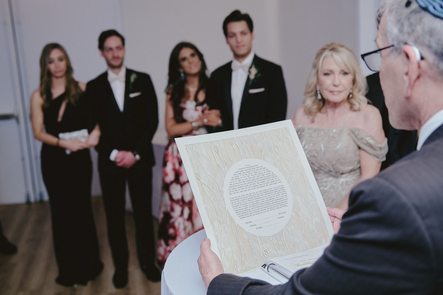 A group of formally dressed people gather during a ceremony while documents are exchanged.
