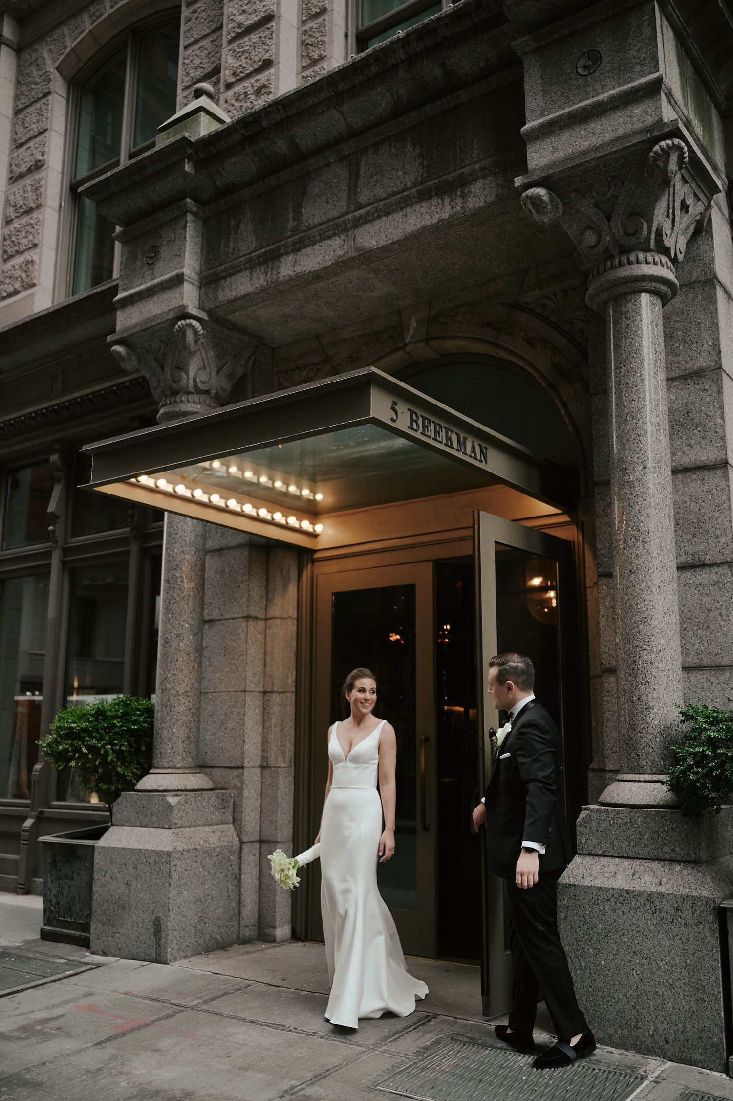 A vintage building entrance with illuminated marquee lighting showcases architectural details and granite columns.