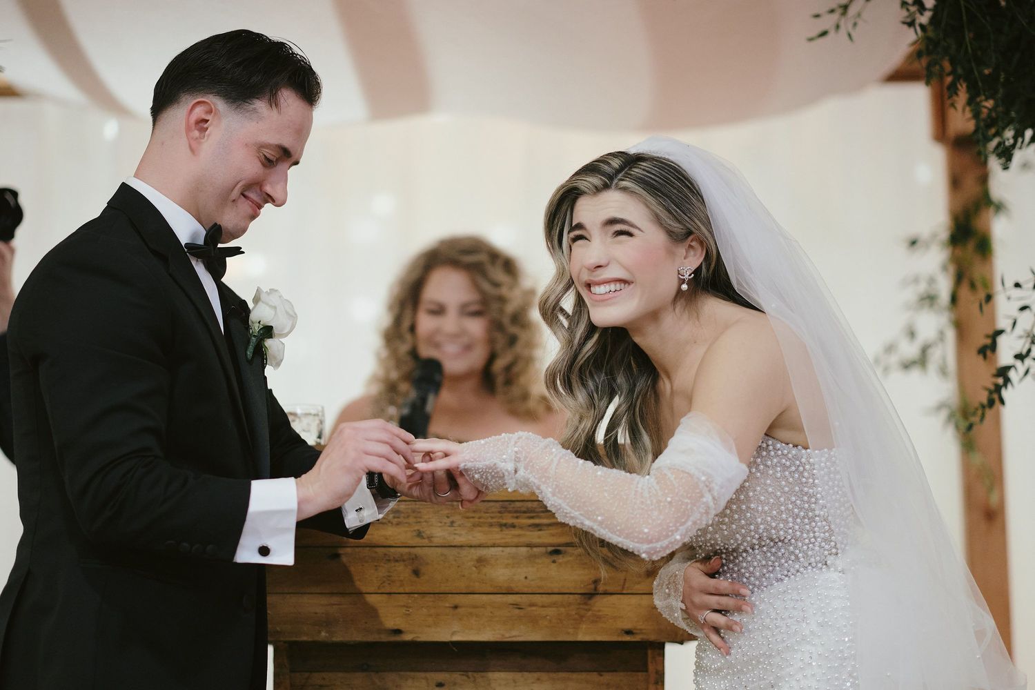A bride and groom share a joyful moment during their wedding ceremony as they exchange rings at the altar.