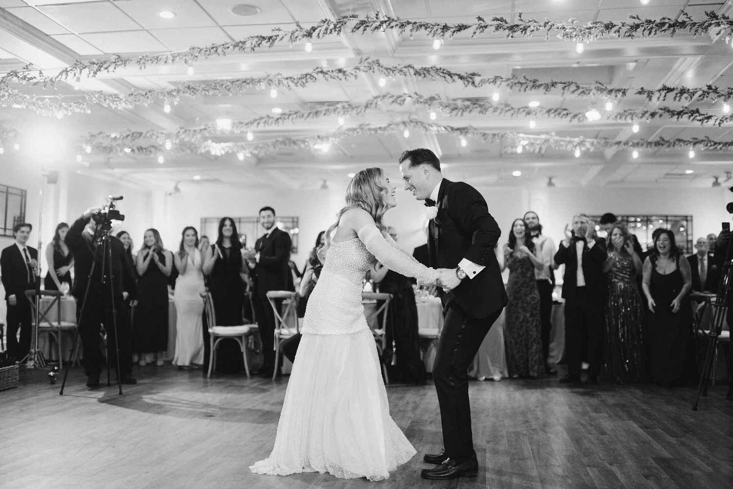 A couple shares their first dance on a beautifully lit dance floor at their wedding reception.