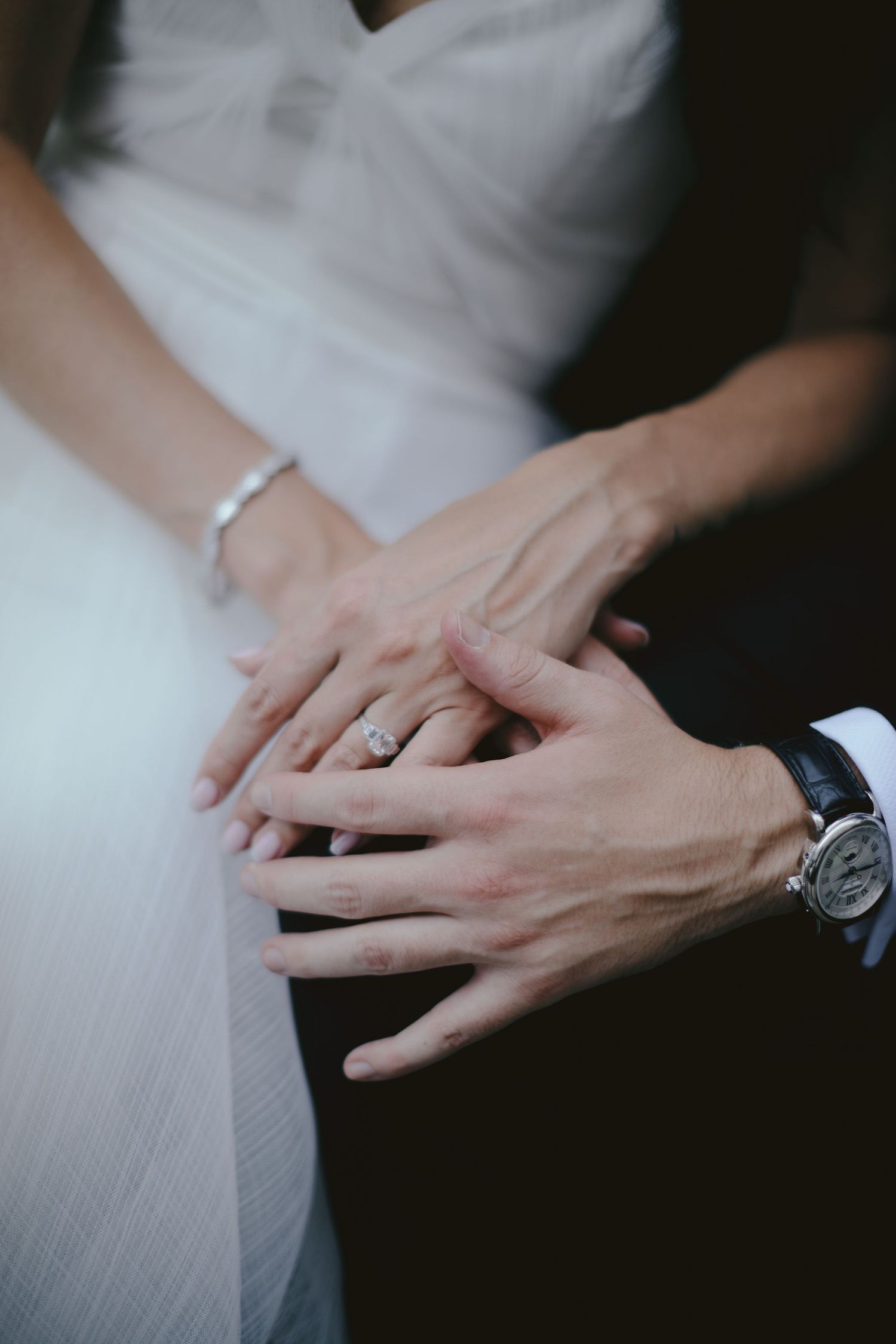 Close up view of hands touching with engagement ring and watch in romantic wedding moment.