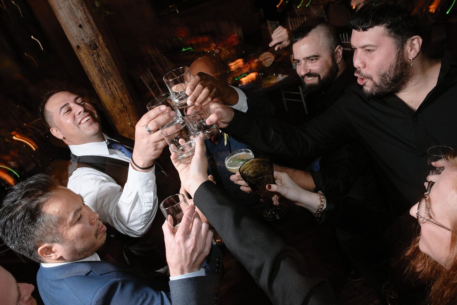 A group raises their glasses together in a celebratory toast during a festive gathering.
