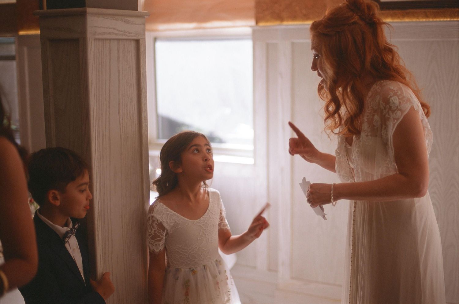 A joyful candid moment with people interacting in a warmly lit interior space near a window.