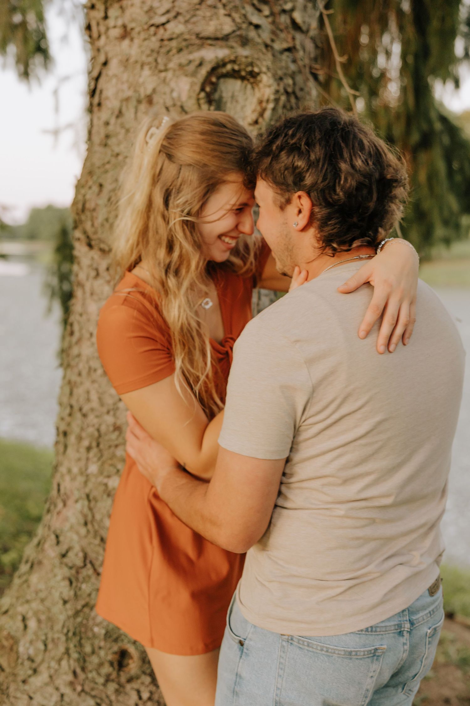 A romantic couple shares an intimate embrace against a tree trunk in a series of four connected photos.