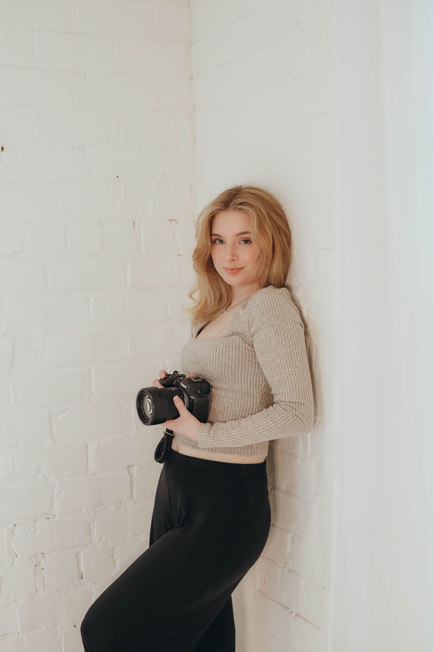 Creative self-portrait series of photographer with camera against white brick wall backdrop.