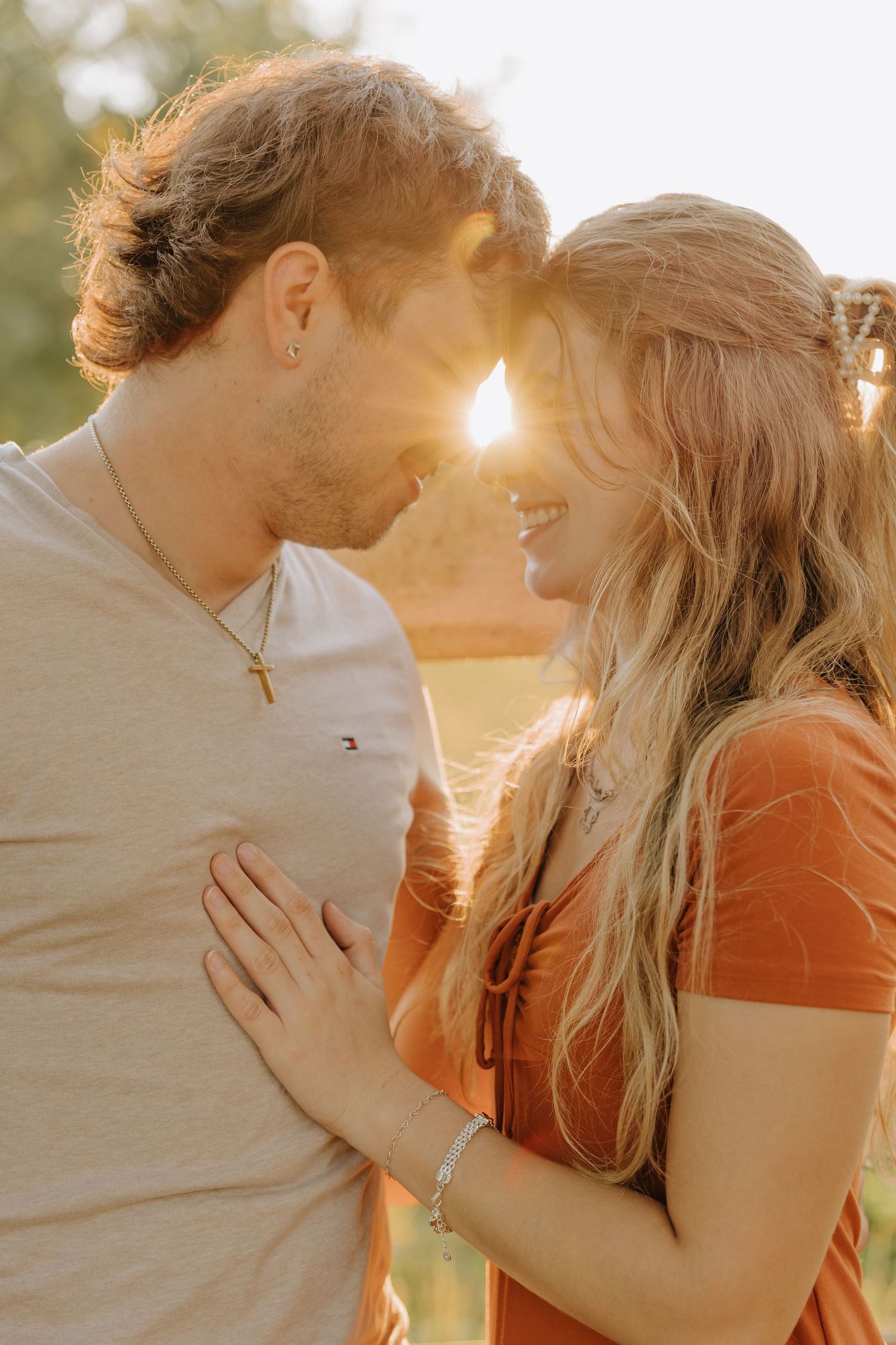 A romantic couple embraces during golden hour sunset, creating a warm and intimate silhouette against the glowing sky.