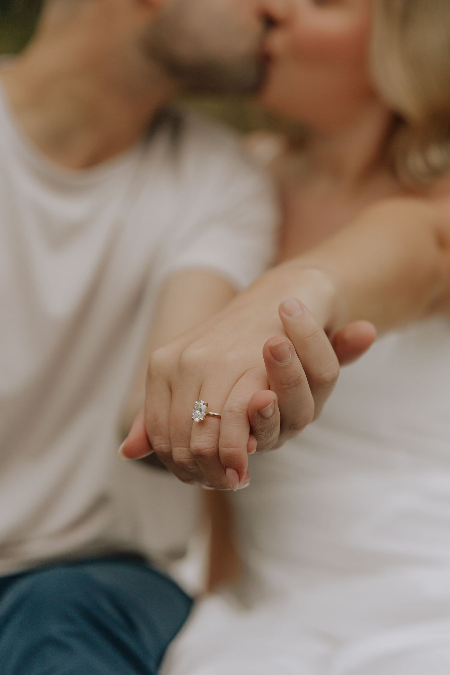 Close-up view of hands showing off an engagement ring with a sparkling diamond in natural lighting.
