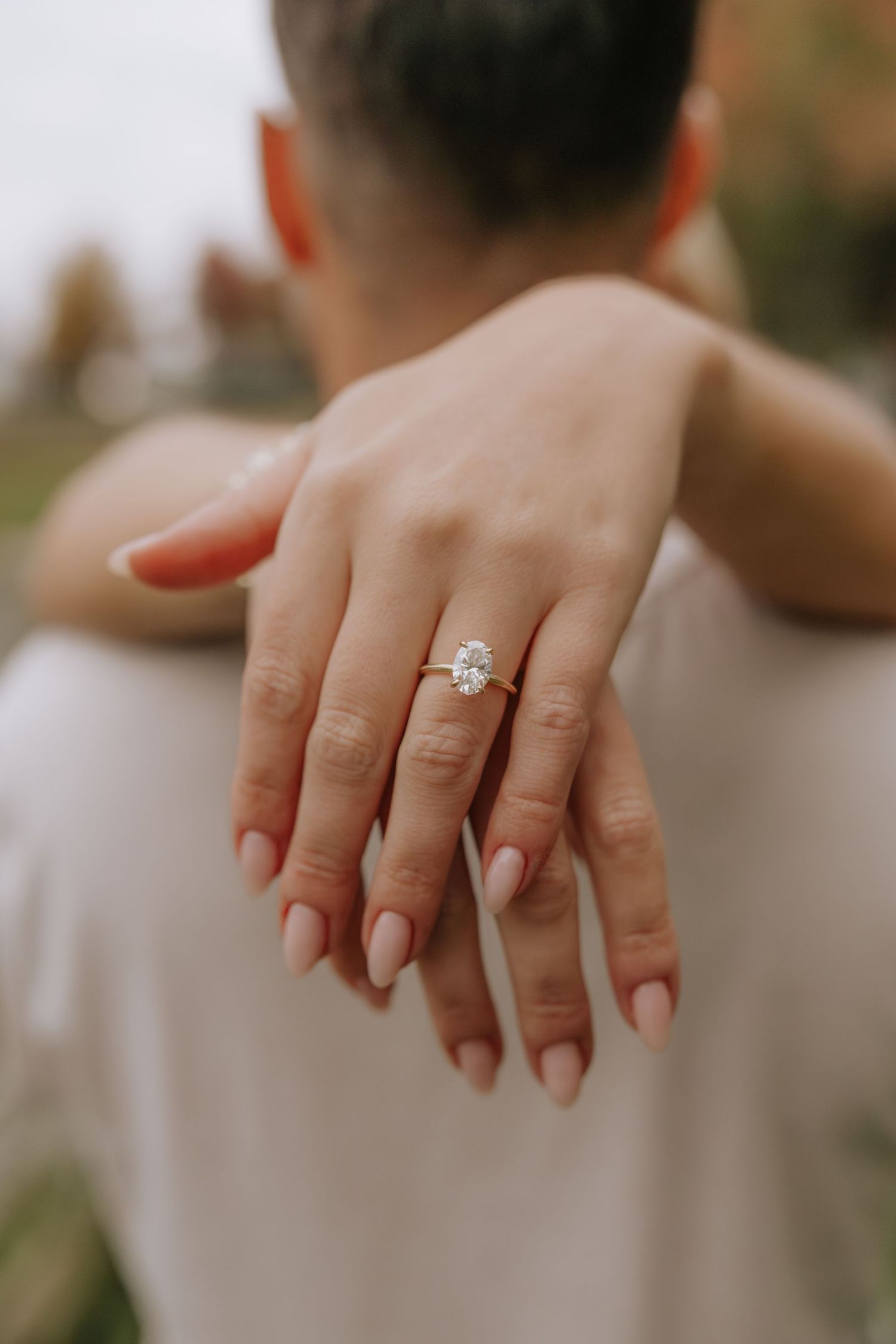 Close-up shots of hands displaying an engagement ring in natural lighting.