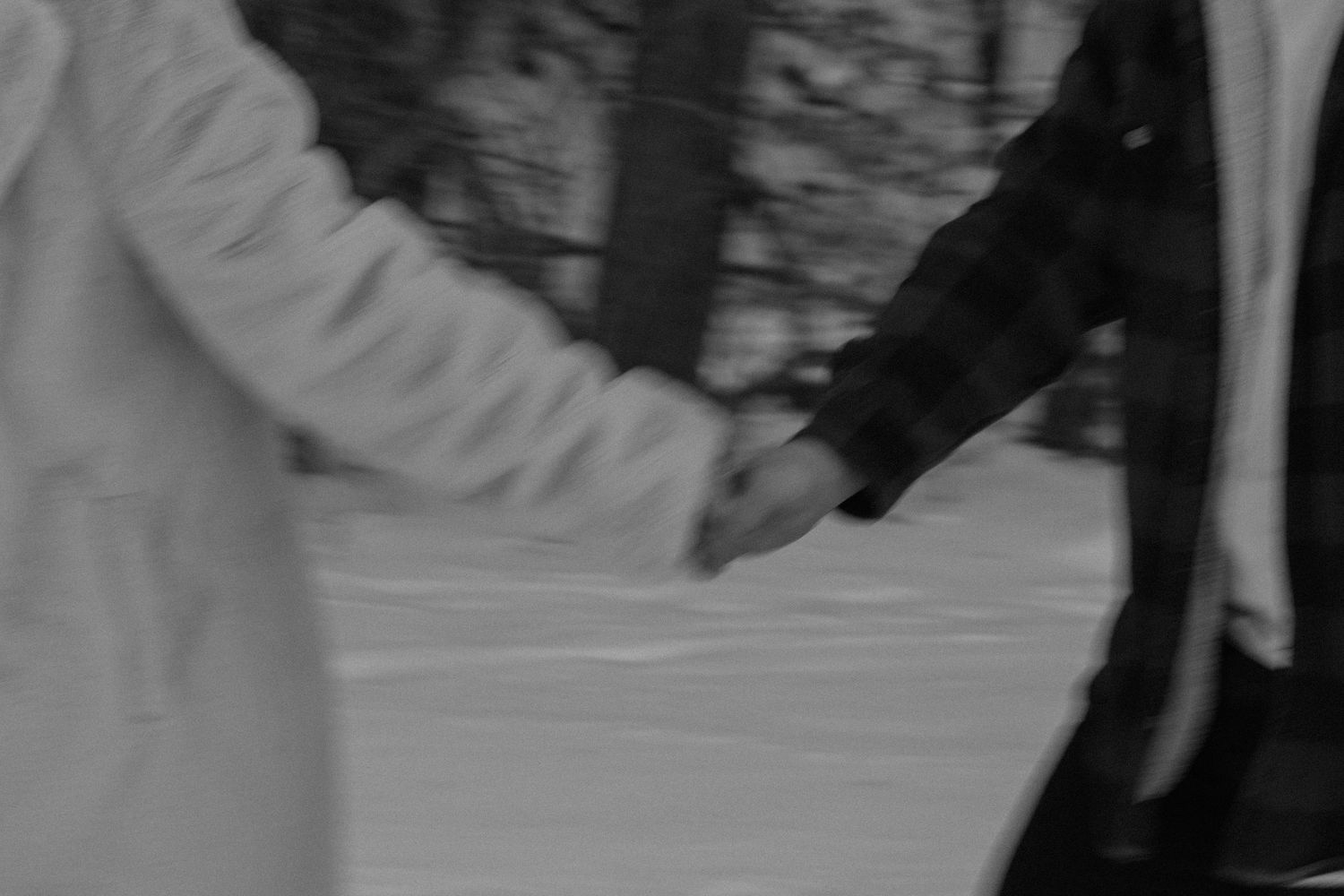 A black and white photograph shows people running while holing hands