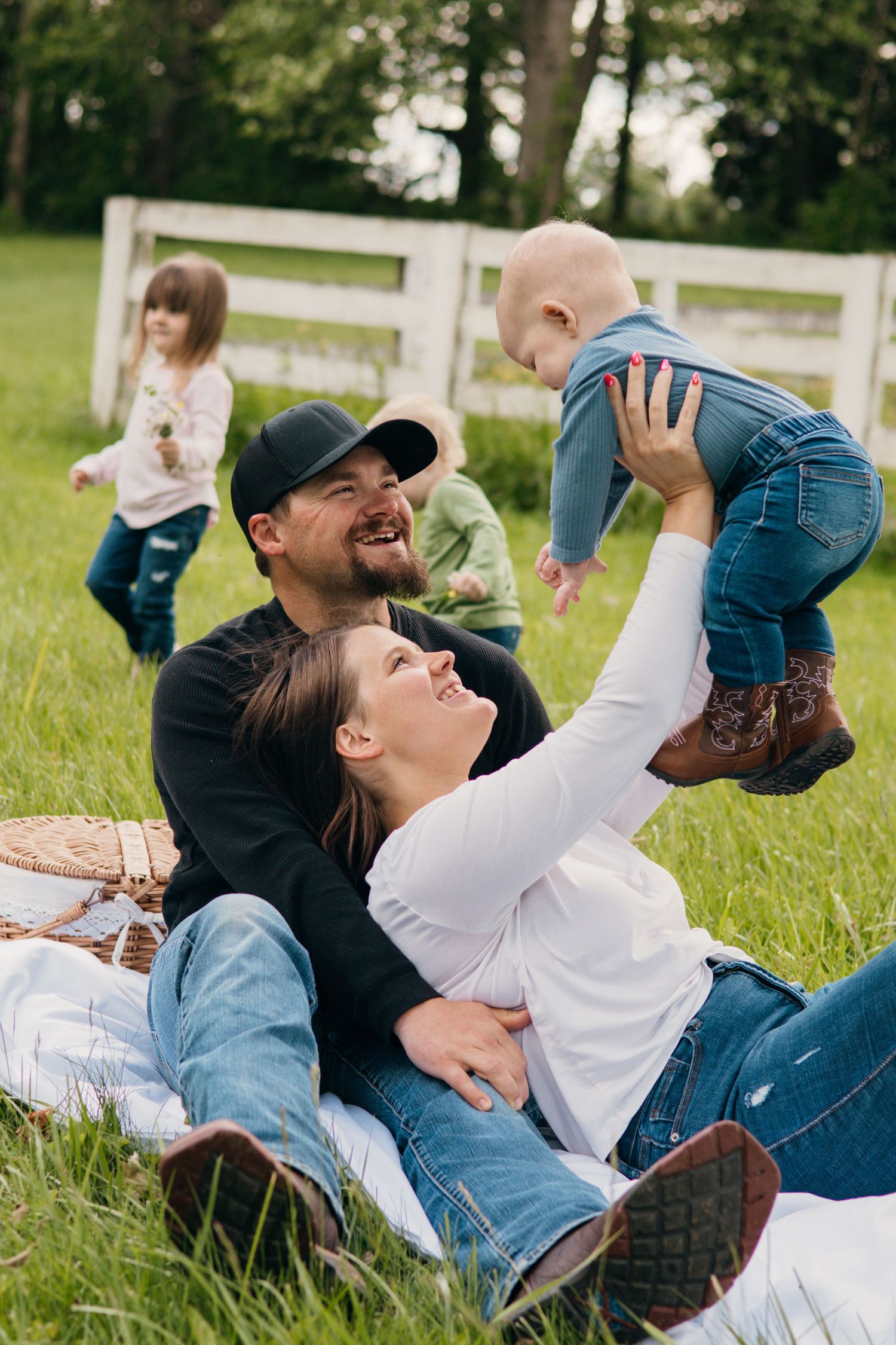 Family members lying in grass laughing and playing during outdoor photo session.