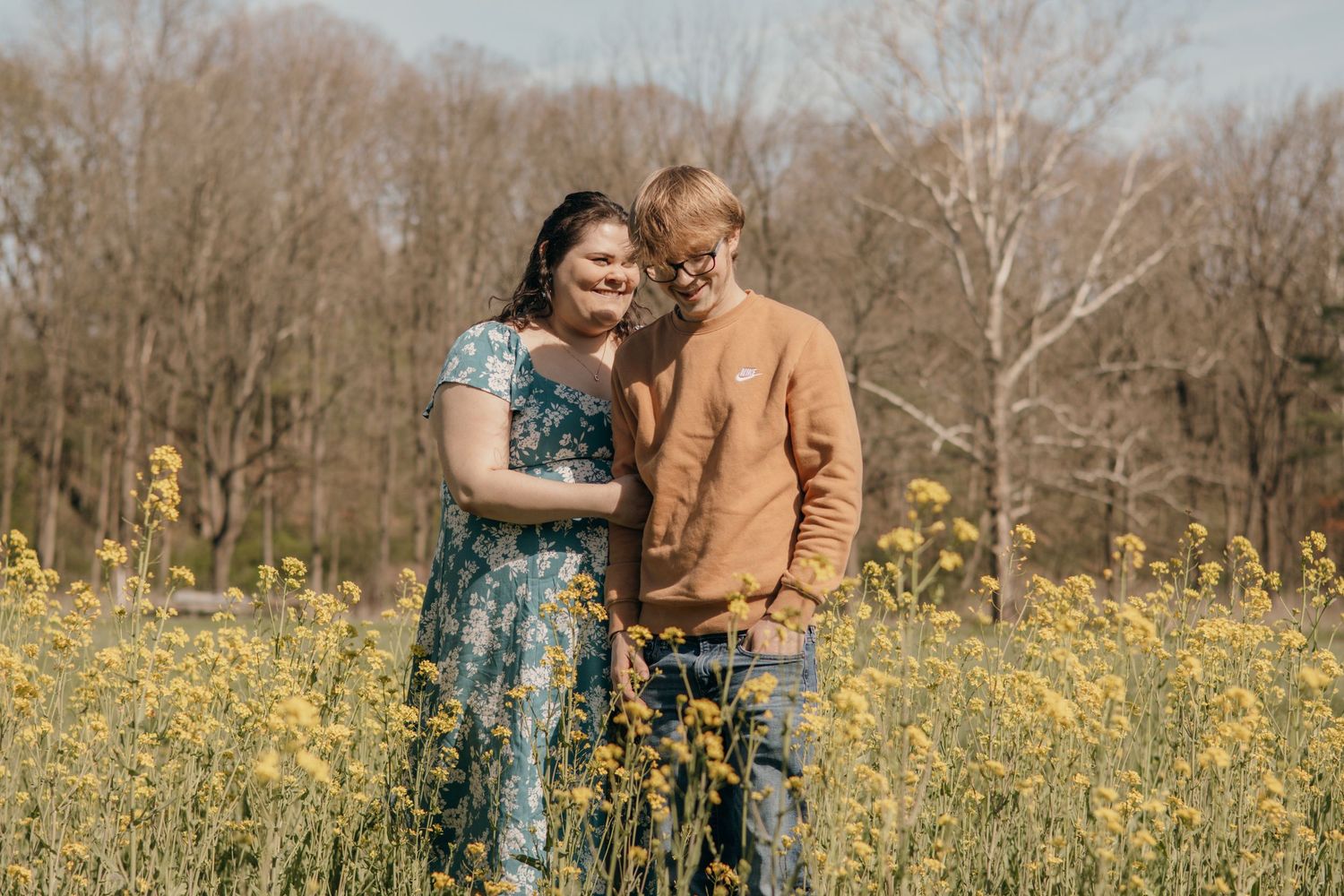 Couple embracing in field of yellow wildflowers on sunny spring day.