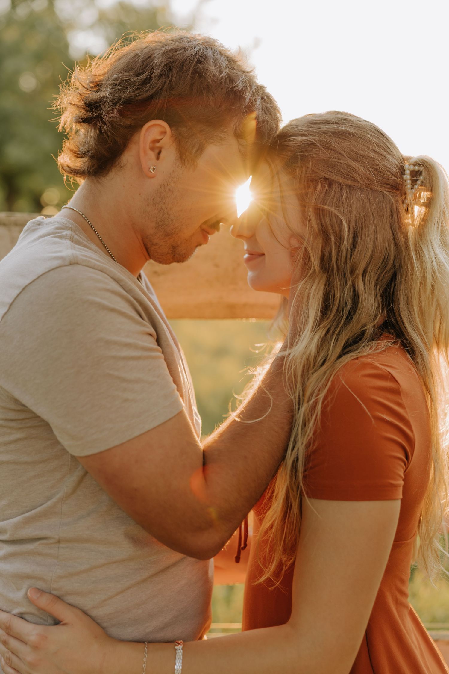A romantic couple embraces during golden hour sunset in a series of intimate outdoor portrait photographs.