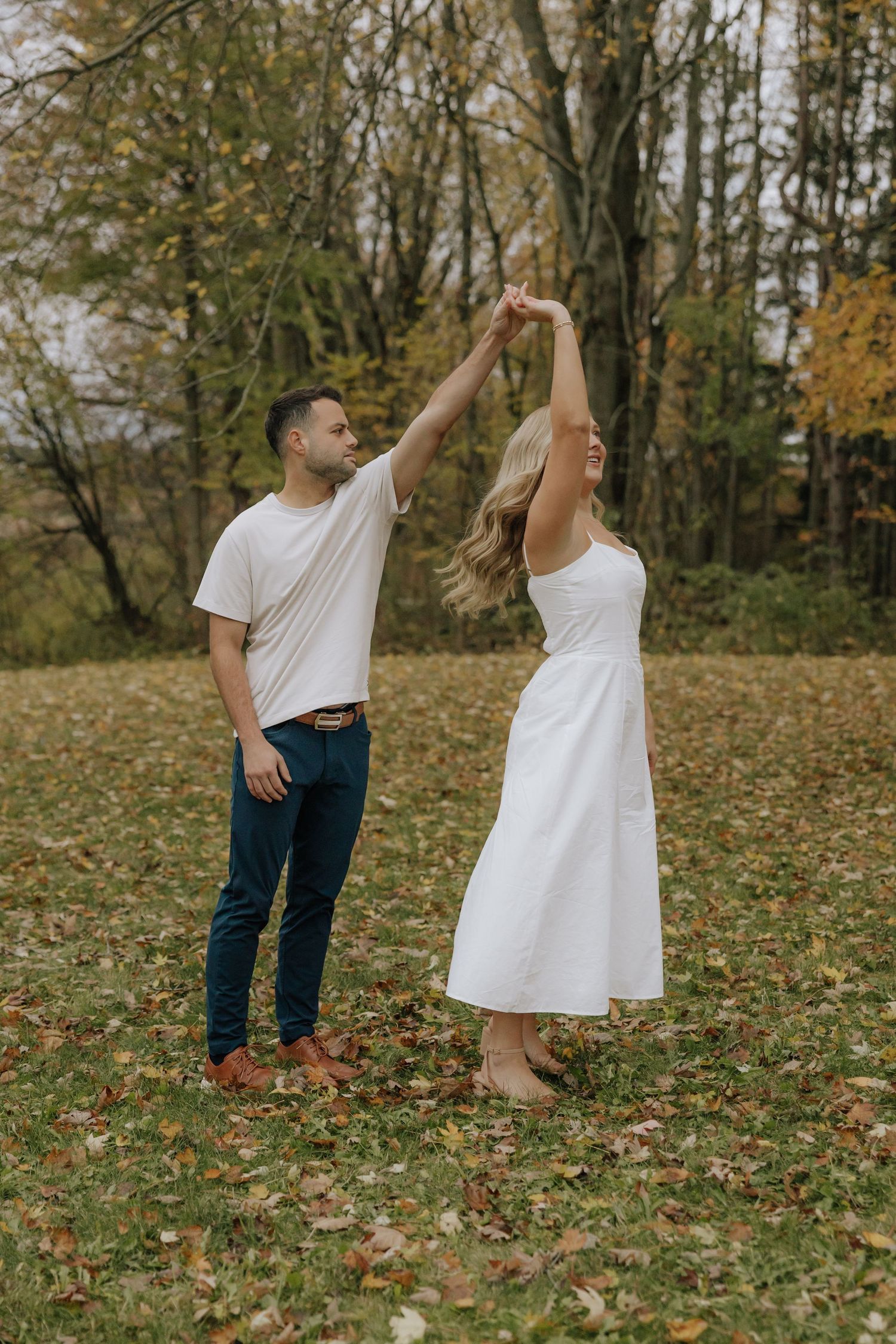 A playful sequence of two people dancing together in a leaf-covered autumn field.
