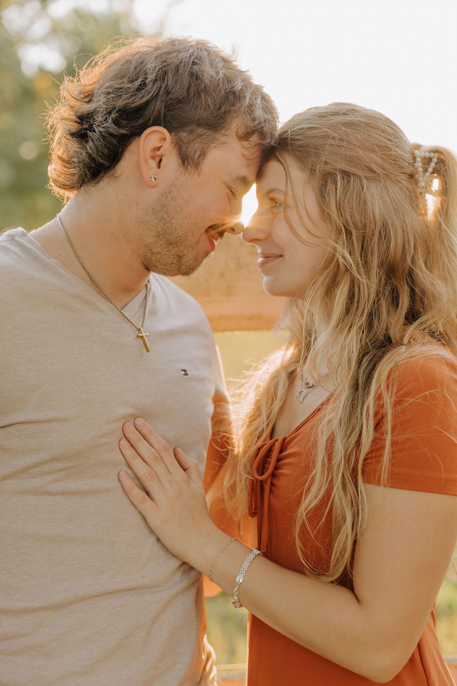 Romantic couple embraces in warm golden sunlight during sunset photoshoot series.