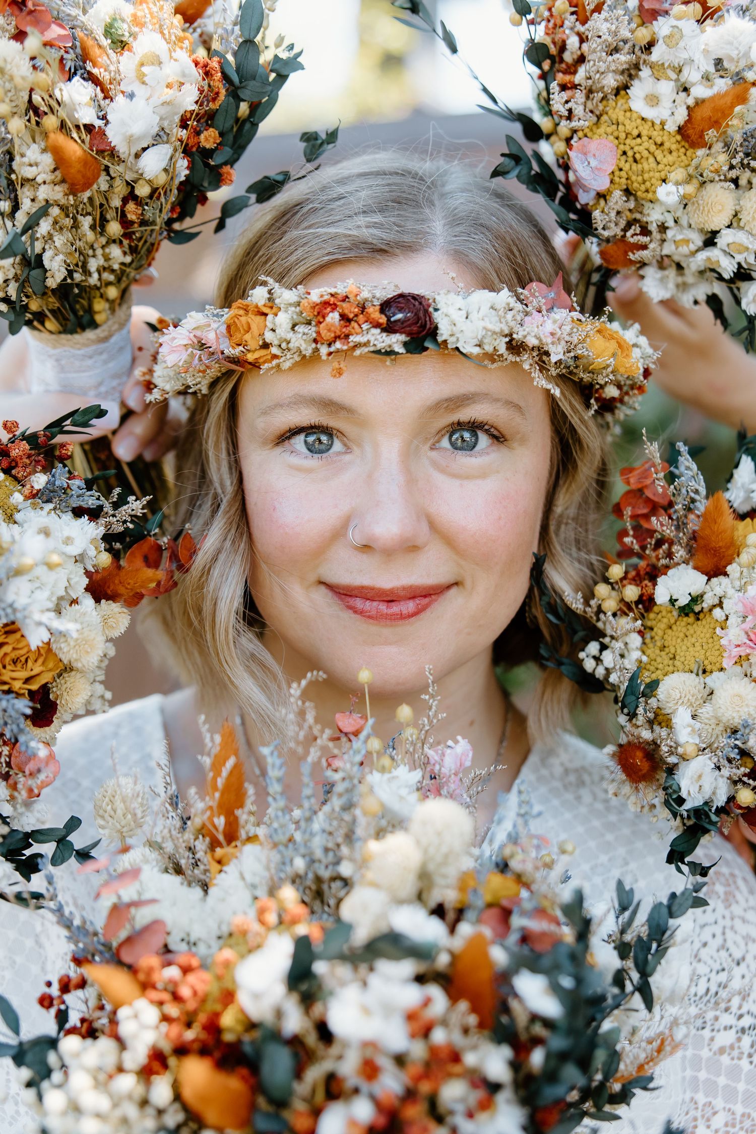 Artistic portrait surrounded by dried flowers and autumn colors in soft ethereal lighting.