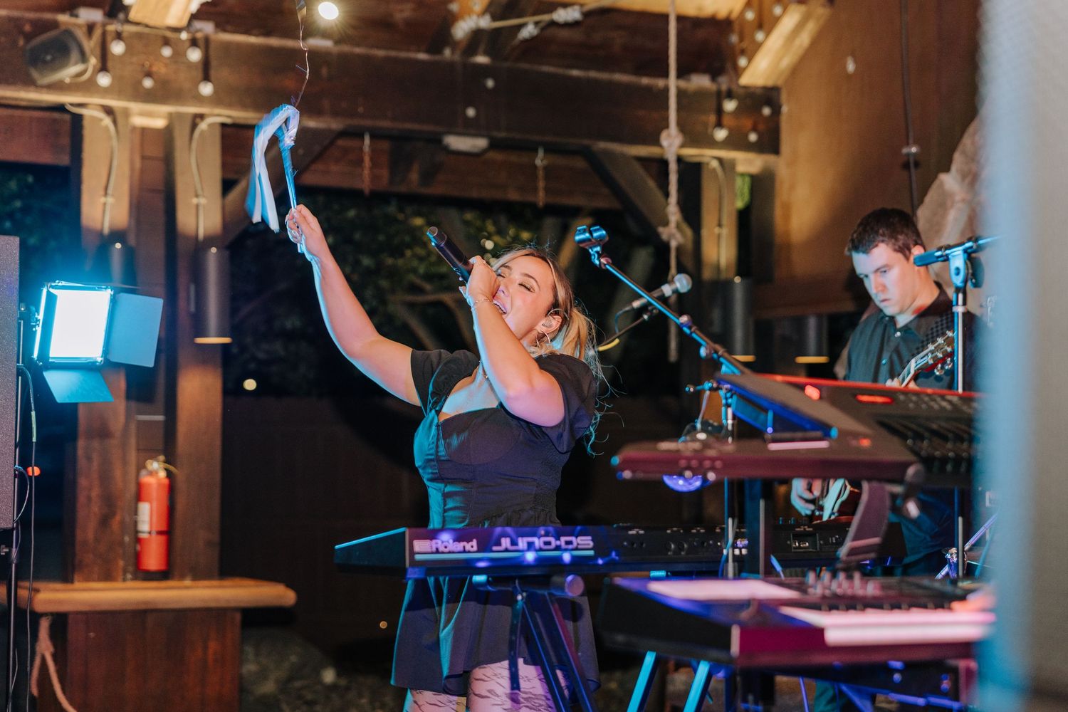 Musicians perform on stage in a dimly lit venue with colorful lighting and instruments.