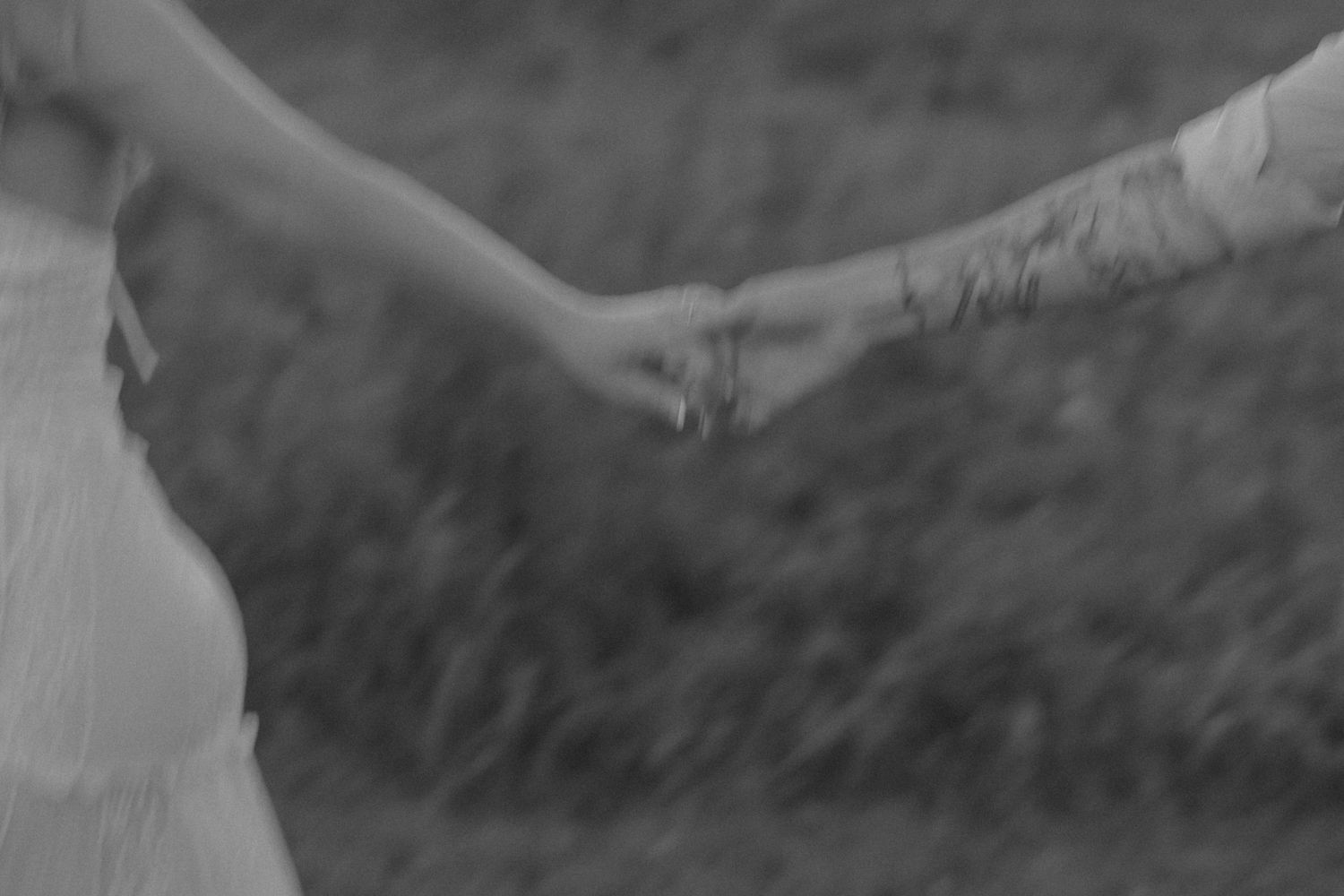 Black and white photo of two people holding hands outdoors, symbolizing love and connection.