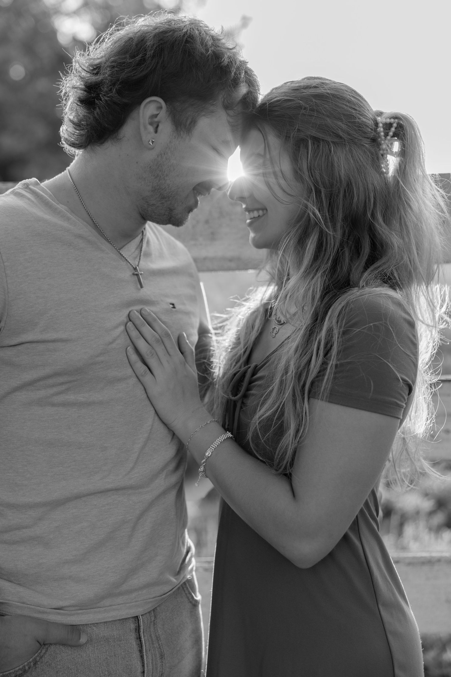 A romantic black and white photo sequence showing a couple embracing and sharing tender moments in sunlit scenery.