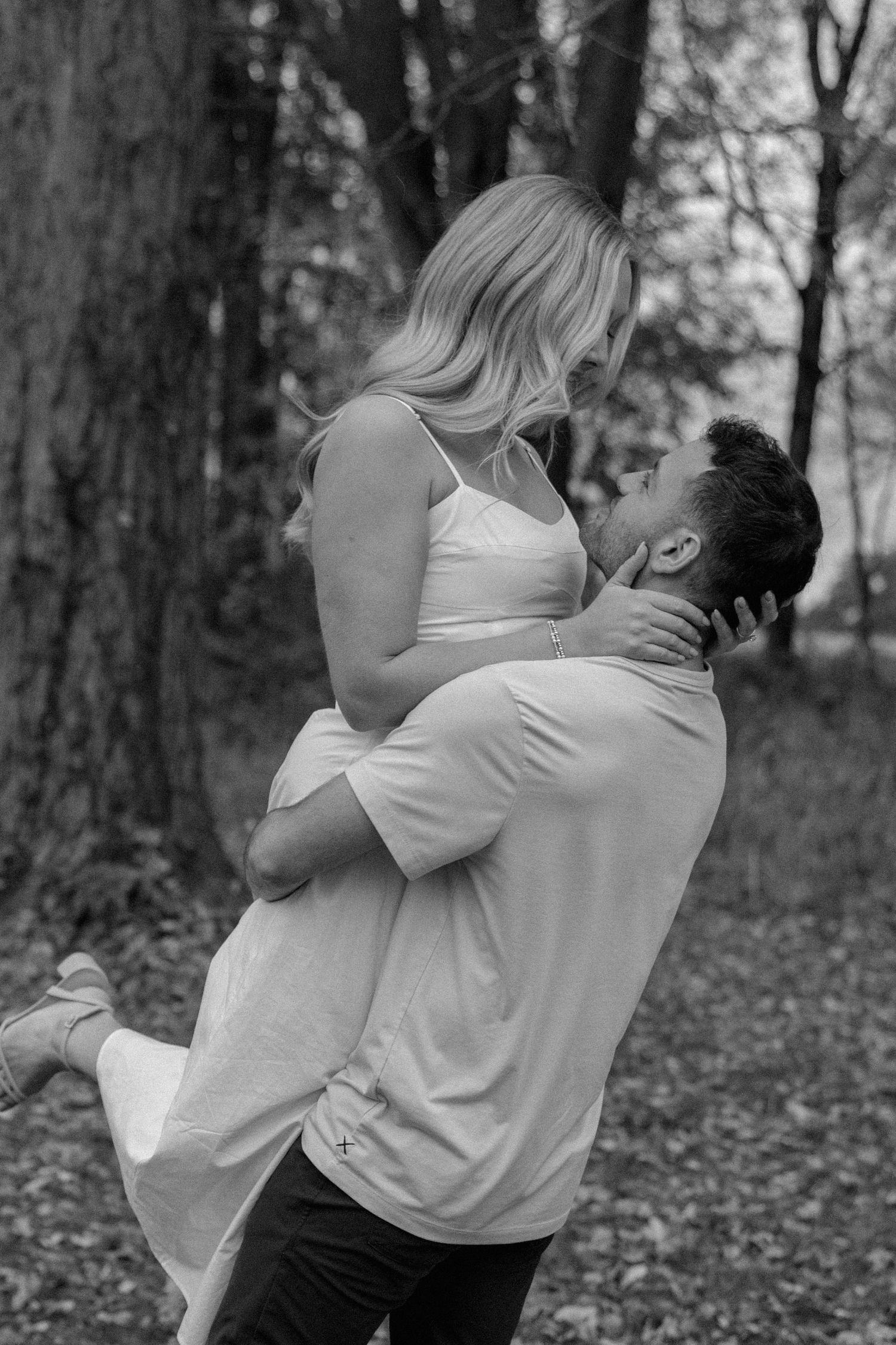 Black and white photos capture playful romantic moments between couple in casual white clothing outdoors.