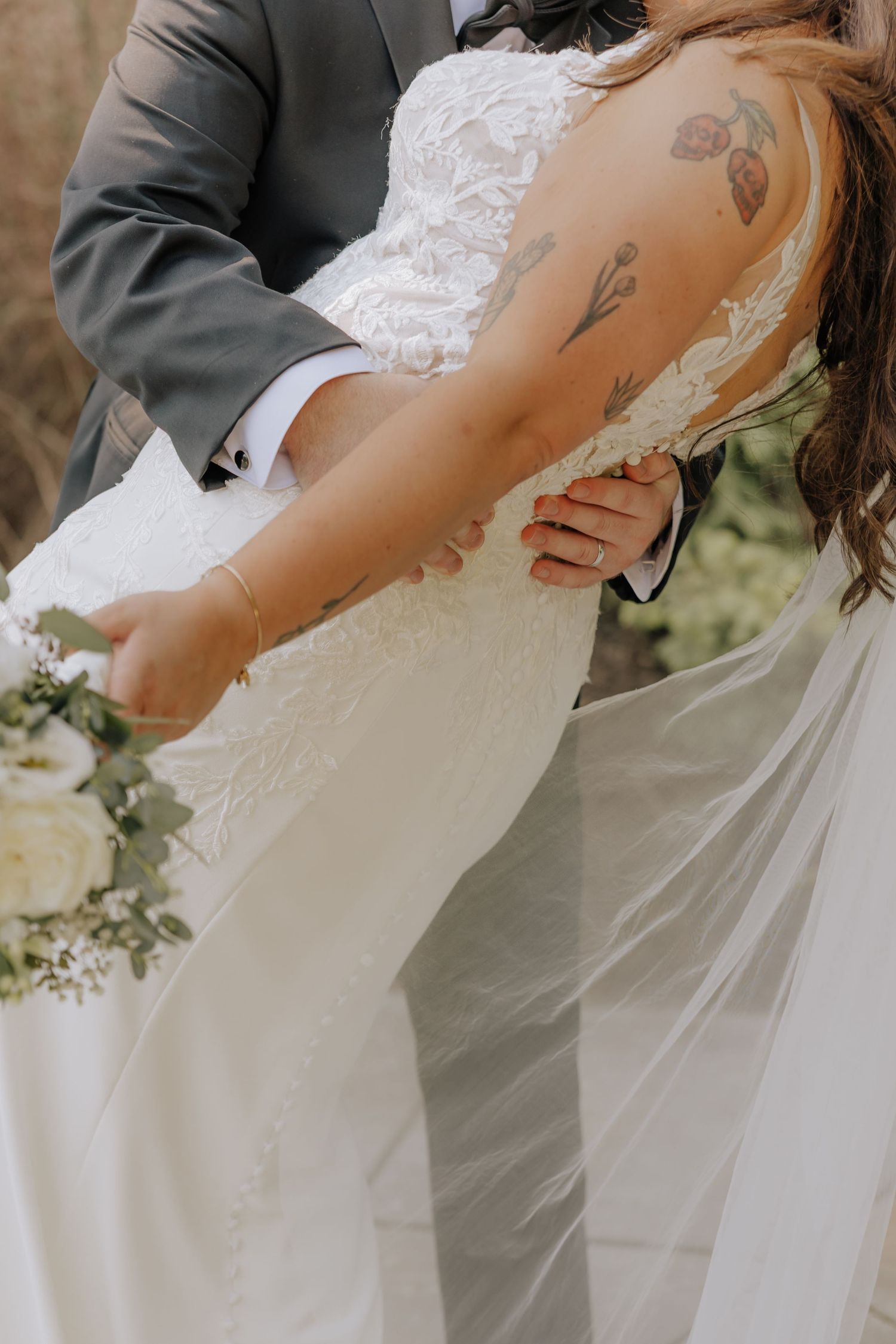 A romantic wedding moment captured as couple shares intimate kiss while bride's white lace veil flows in the breeze.