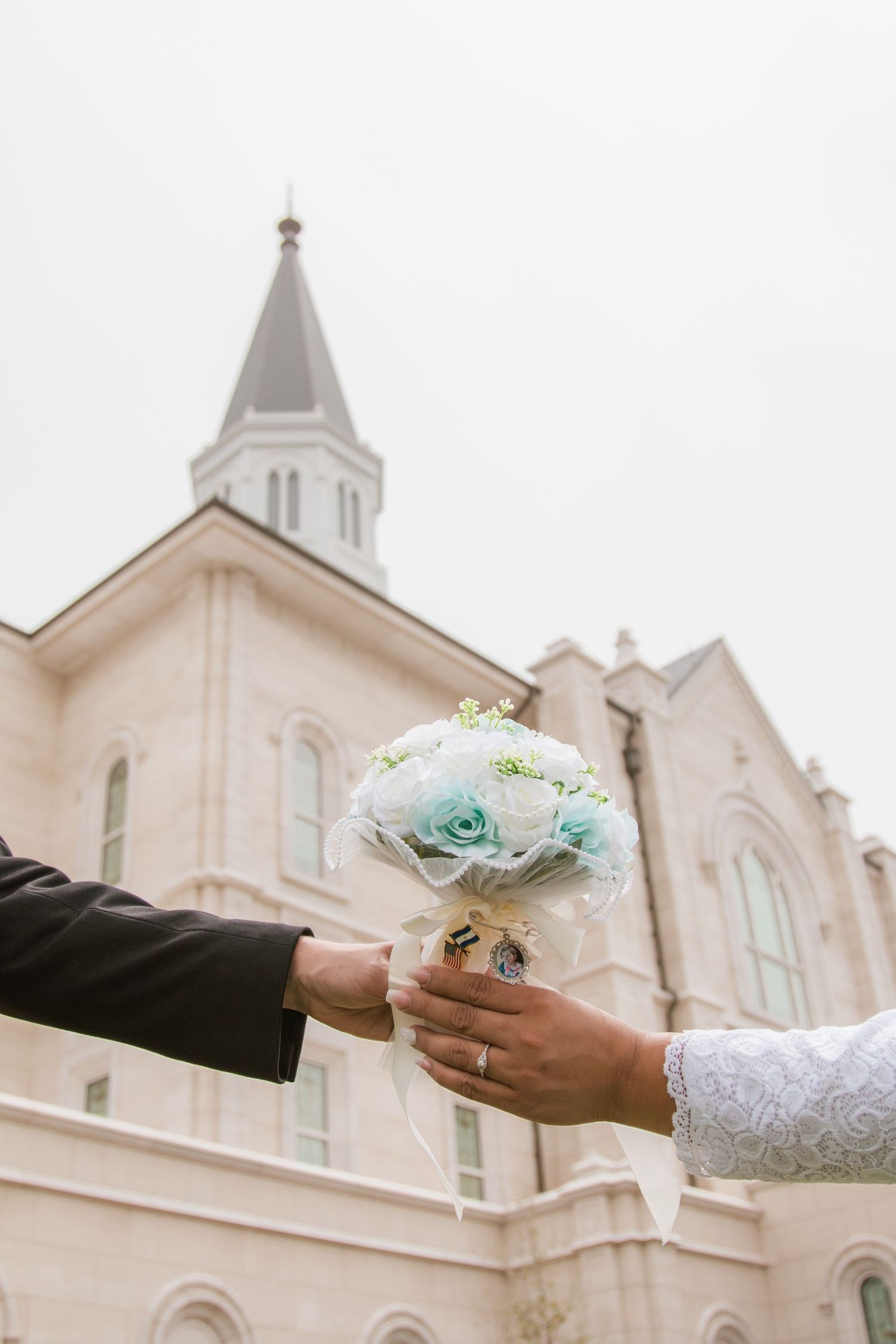Wedding ceremony details outside white church with bouquet exchange.