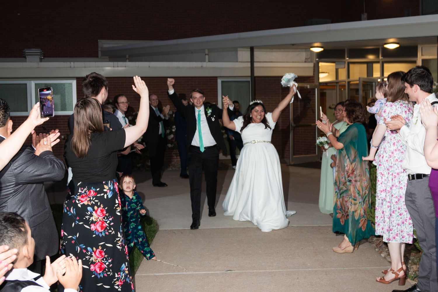 Wedding reception dance floor with guests celebrating in evening lighting.