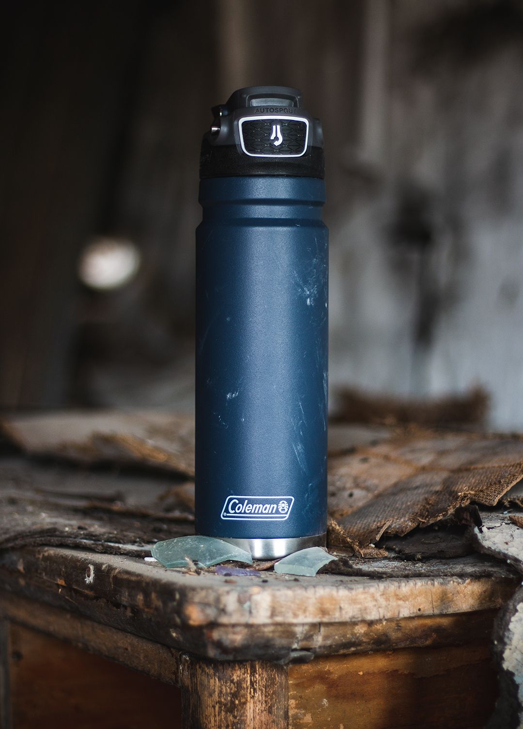 Blue Coleman water bottle sitting on rustic wooden surface.