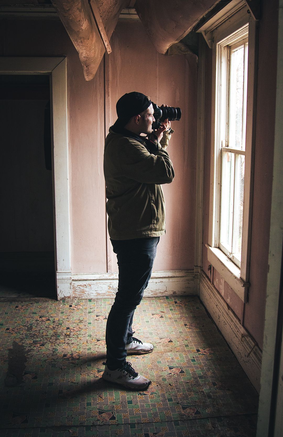 Silhouette of photographer taking pictures through window in abandoned building.