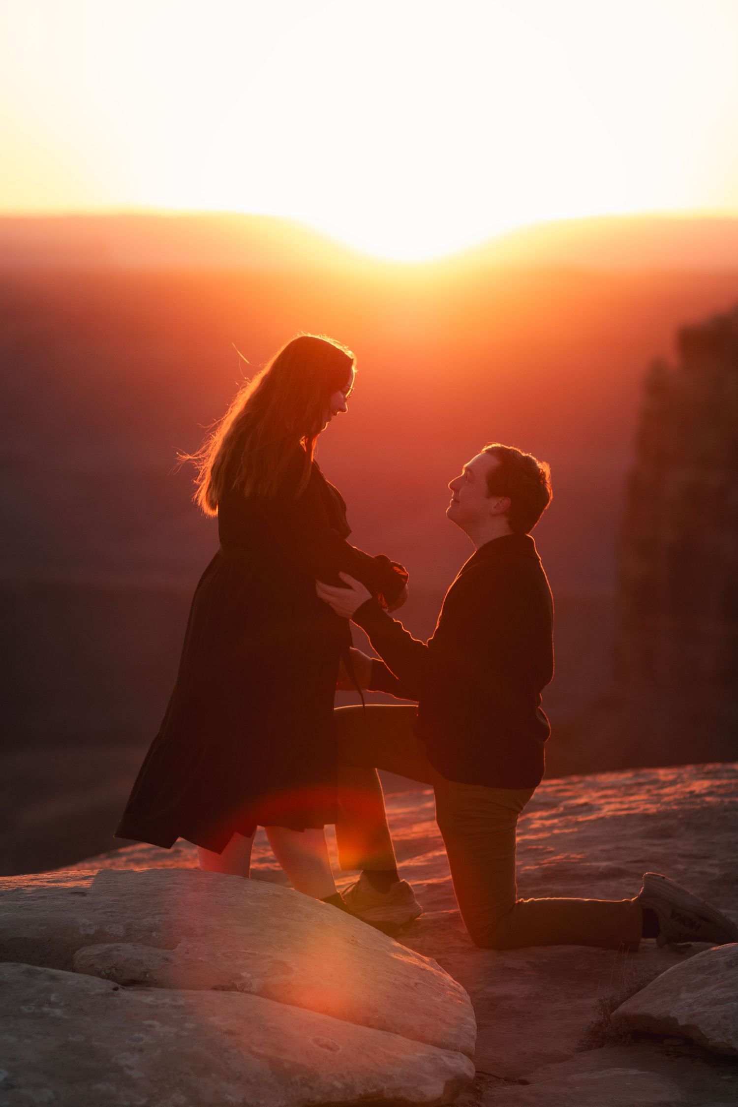 Silhouettes of a couple embrace during a stunning desert sunset.