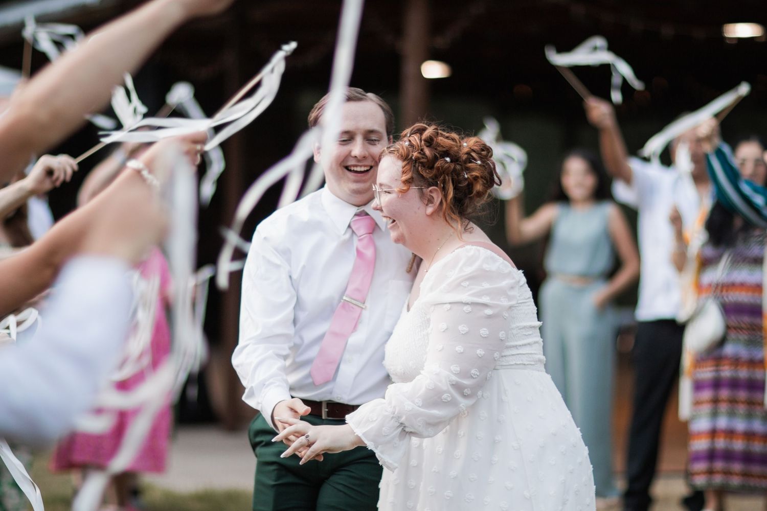 Wedding guests dancing and celebrating at an outdoor reception with festive decorations.