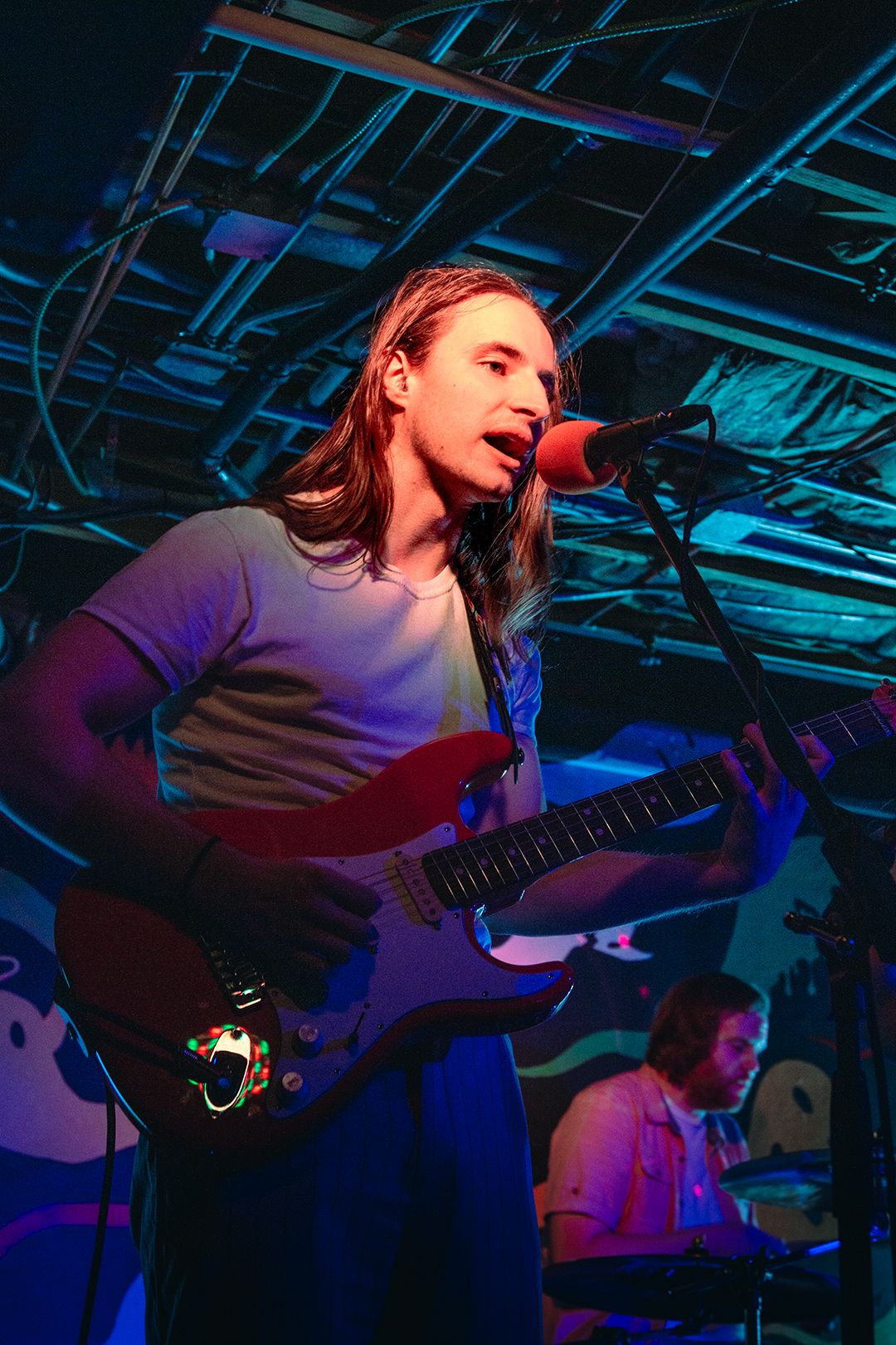 Energetic live music performance with guitarist on stage under blue lighting.