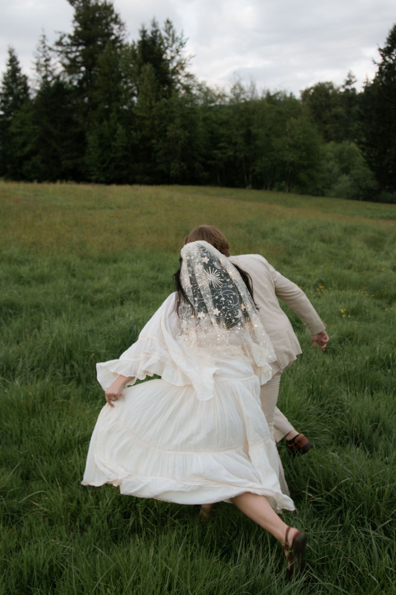 A flowy white dress billows in the breeze as someone lies in a green meadow.