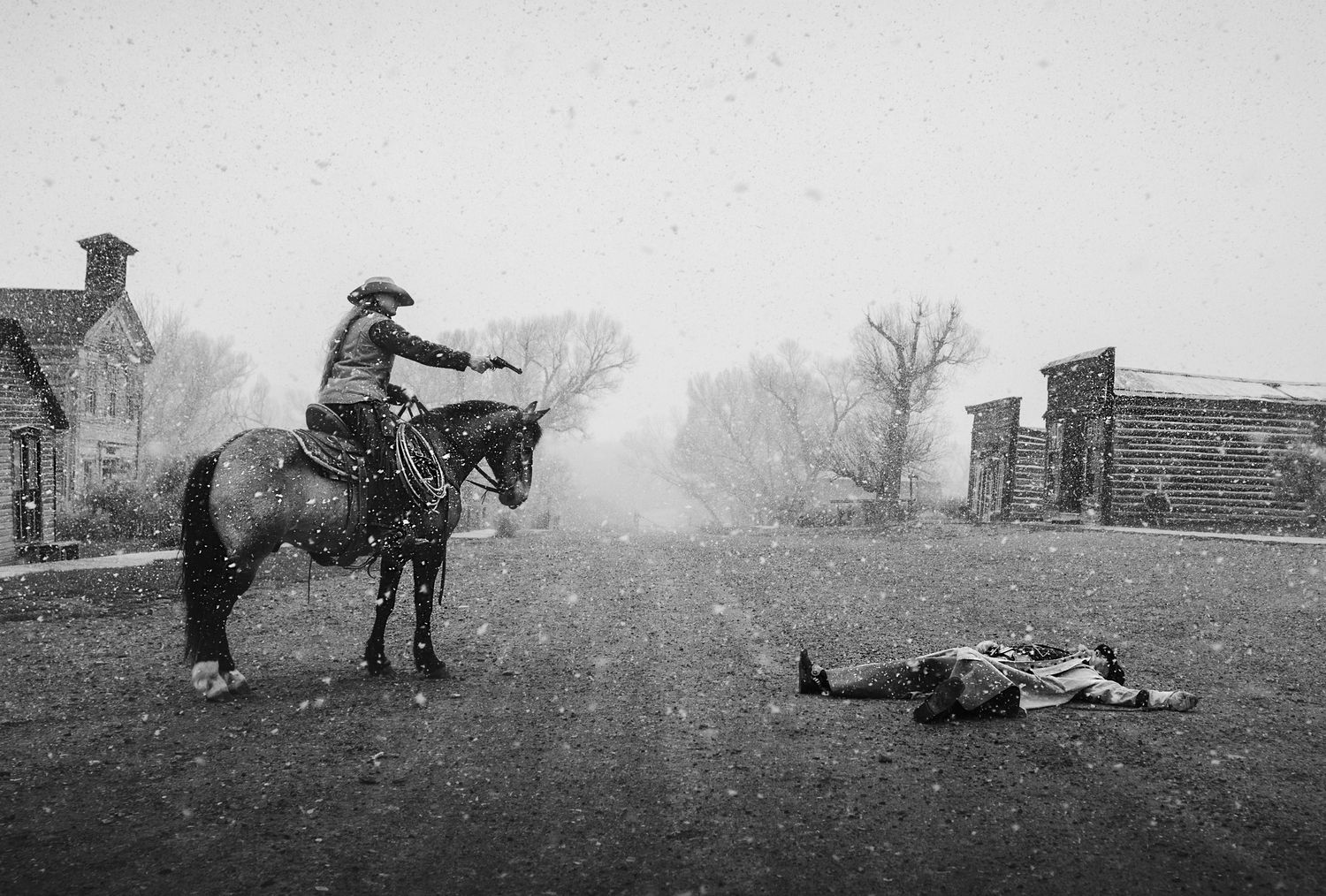 A dramatic black and white Western scene of a lone rider on horseback in the misty countryside.