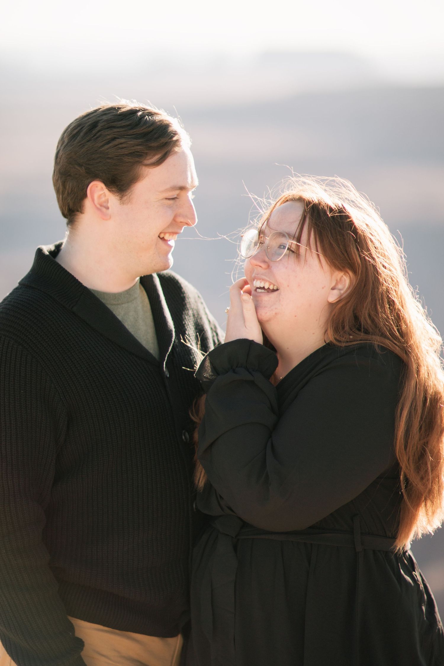 Candid moment of a couple laughing together during a winter photoshoot.