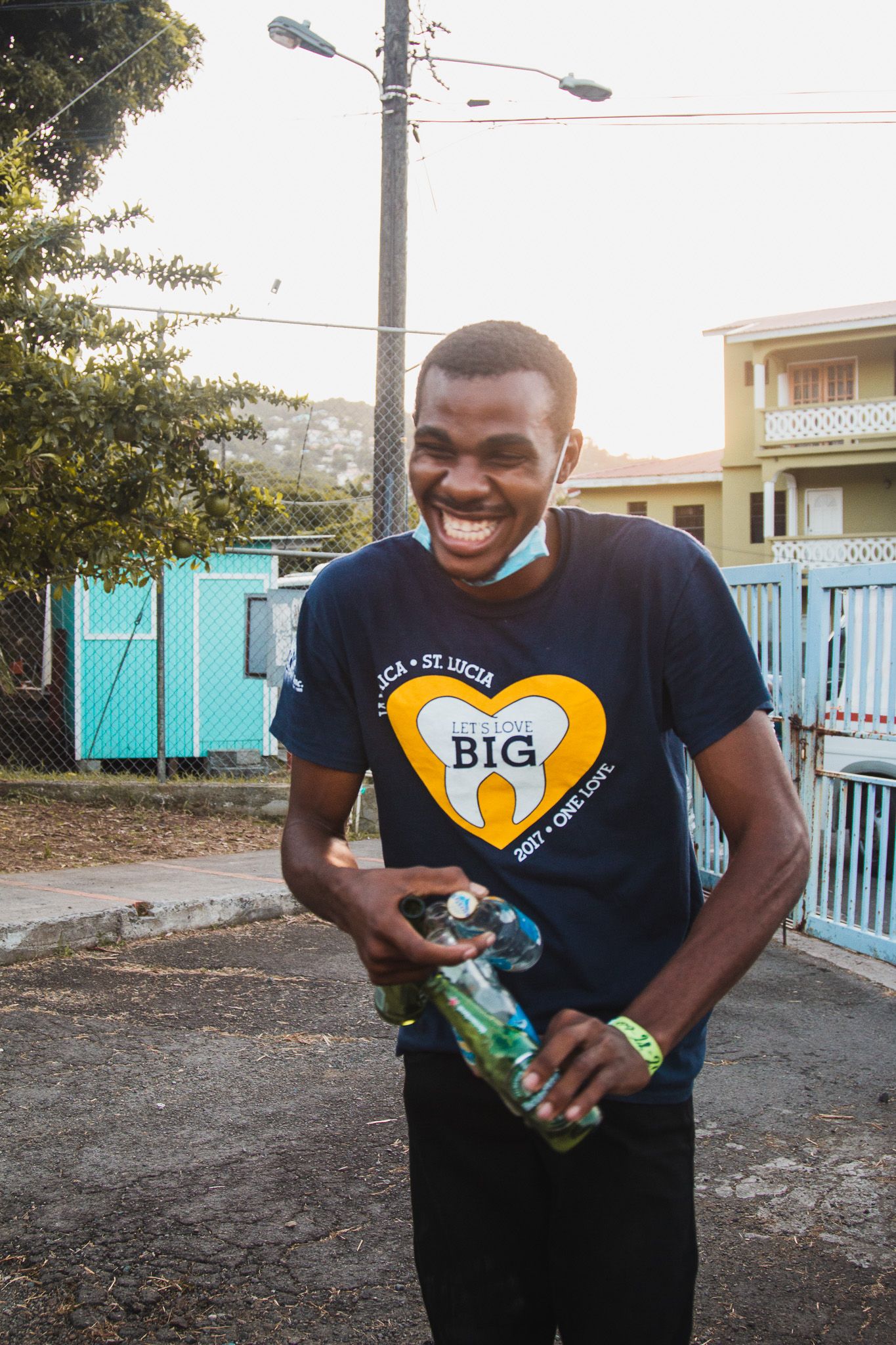 Person in navy shirt with heart logo laughing joyfully outdoors.