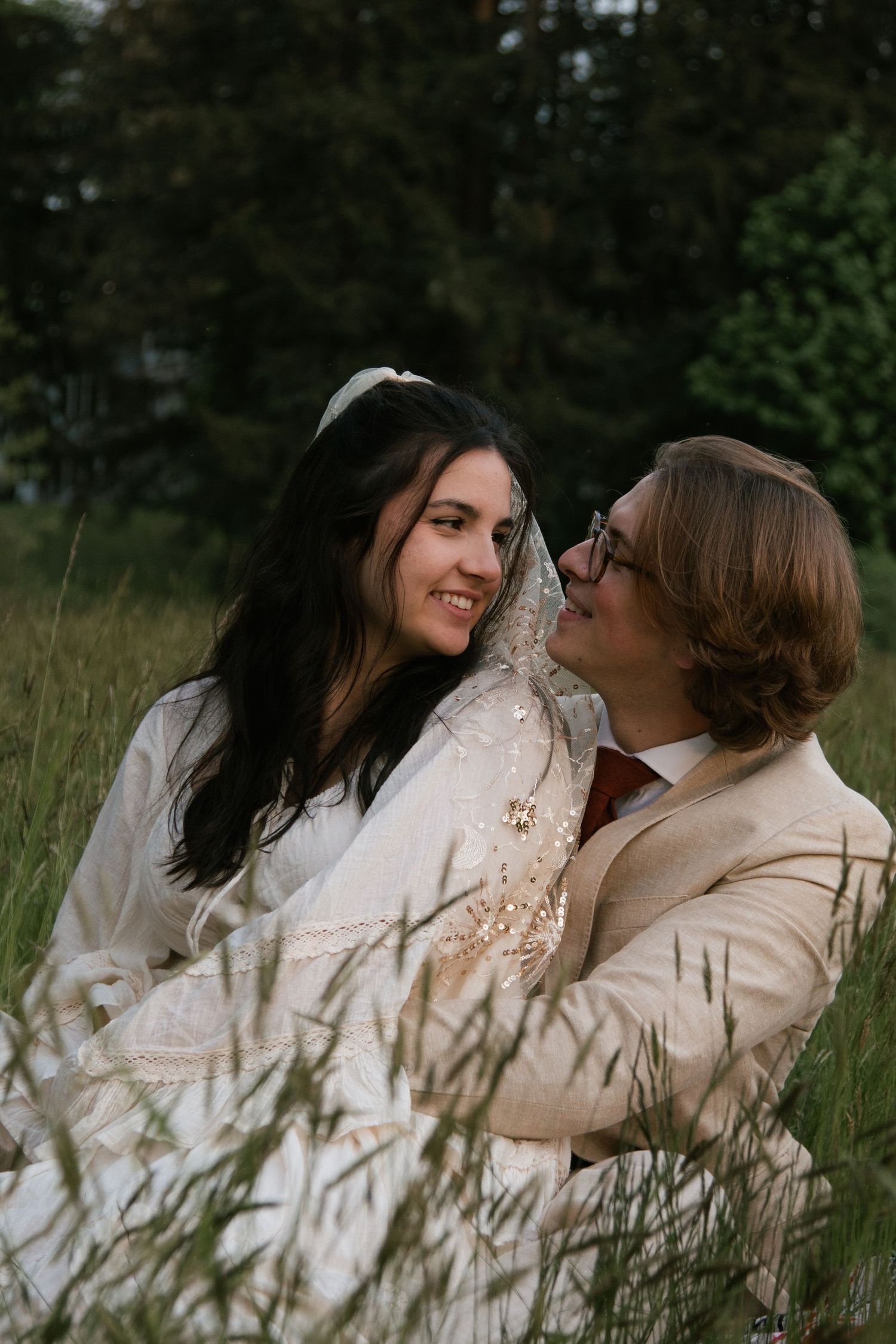 A tender moment shared between two people in a meadow of tall grass.