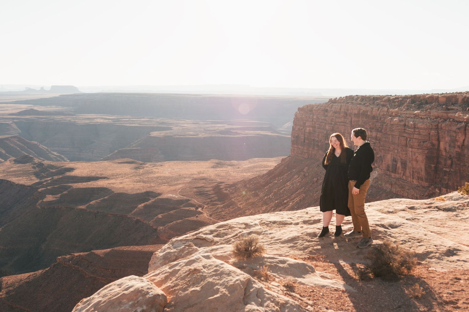 Scenic overlook of vast canyonlands and desert landscape at sunset.