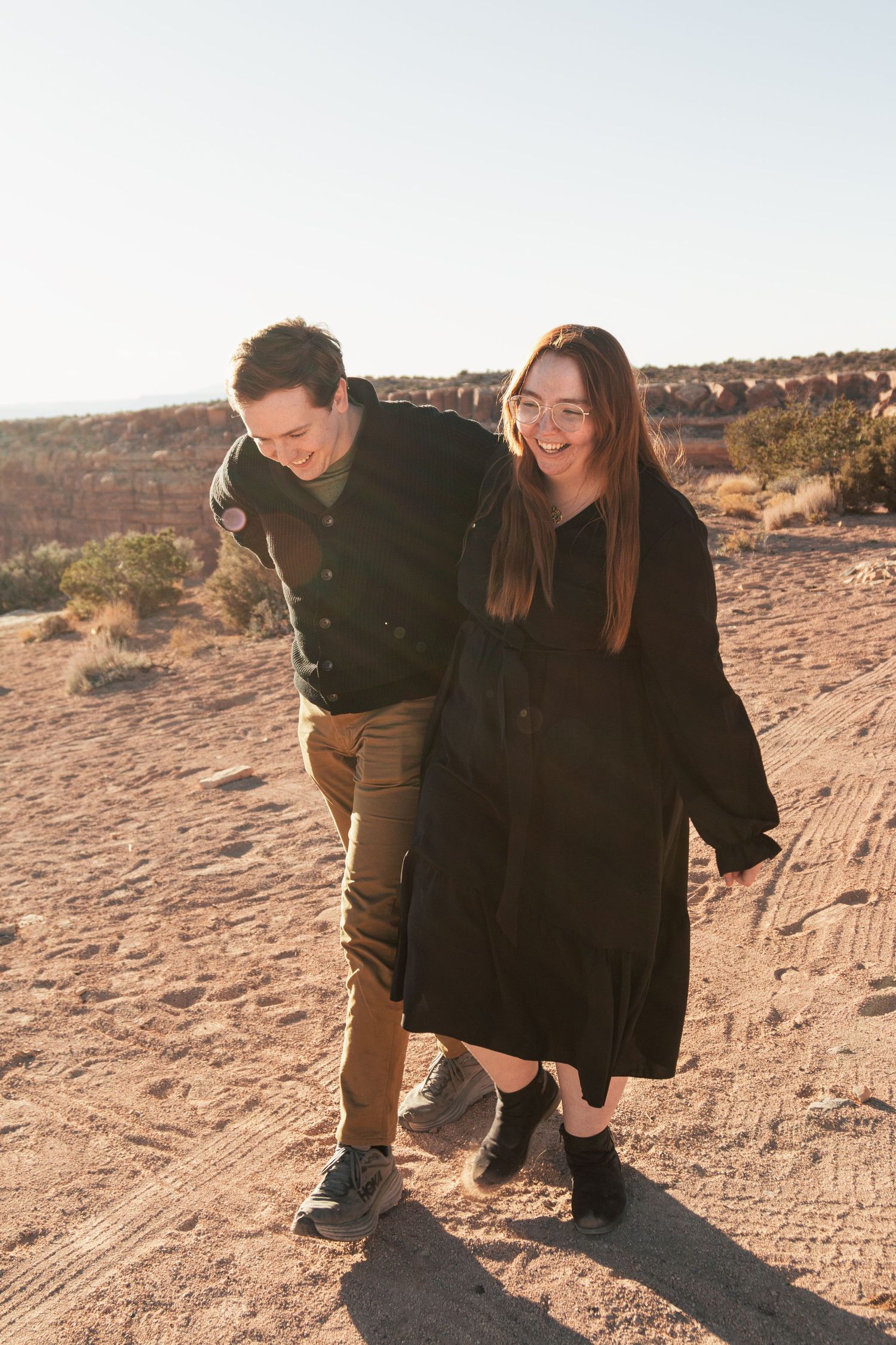 Couple shares cheerful moment together in desert landscape with warm afternoon light.